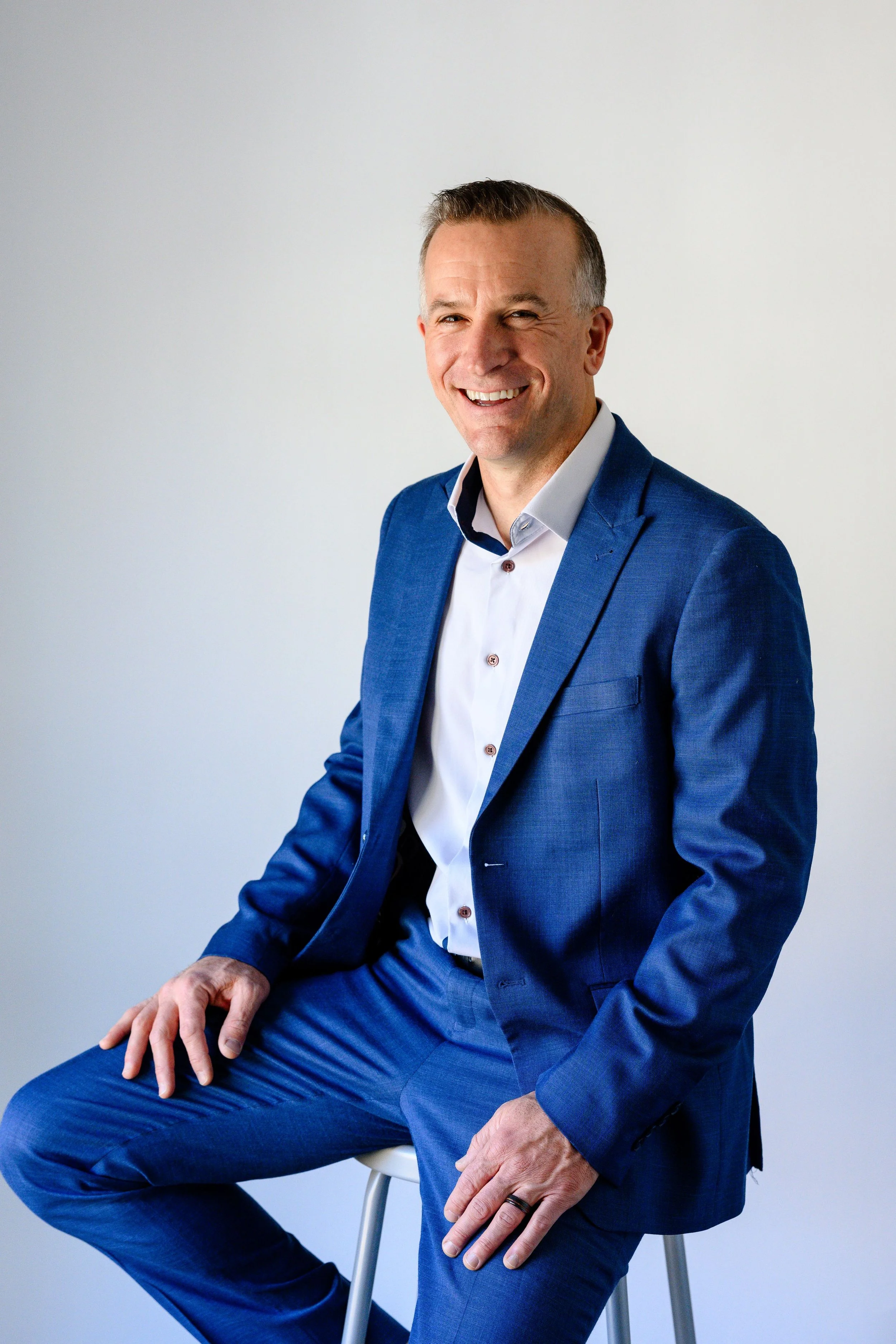 Adam Hill posing for a camera in a blue suit.