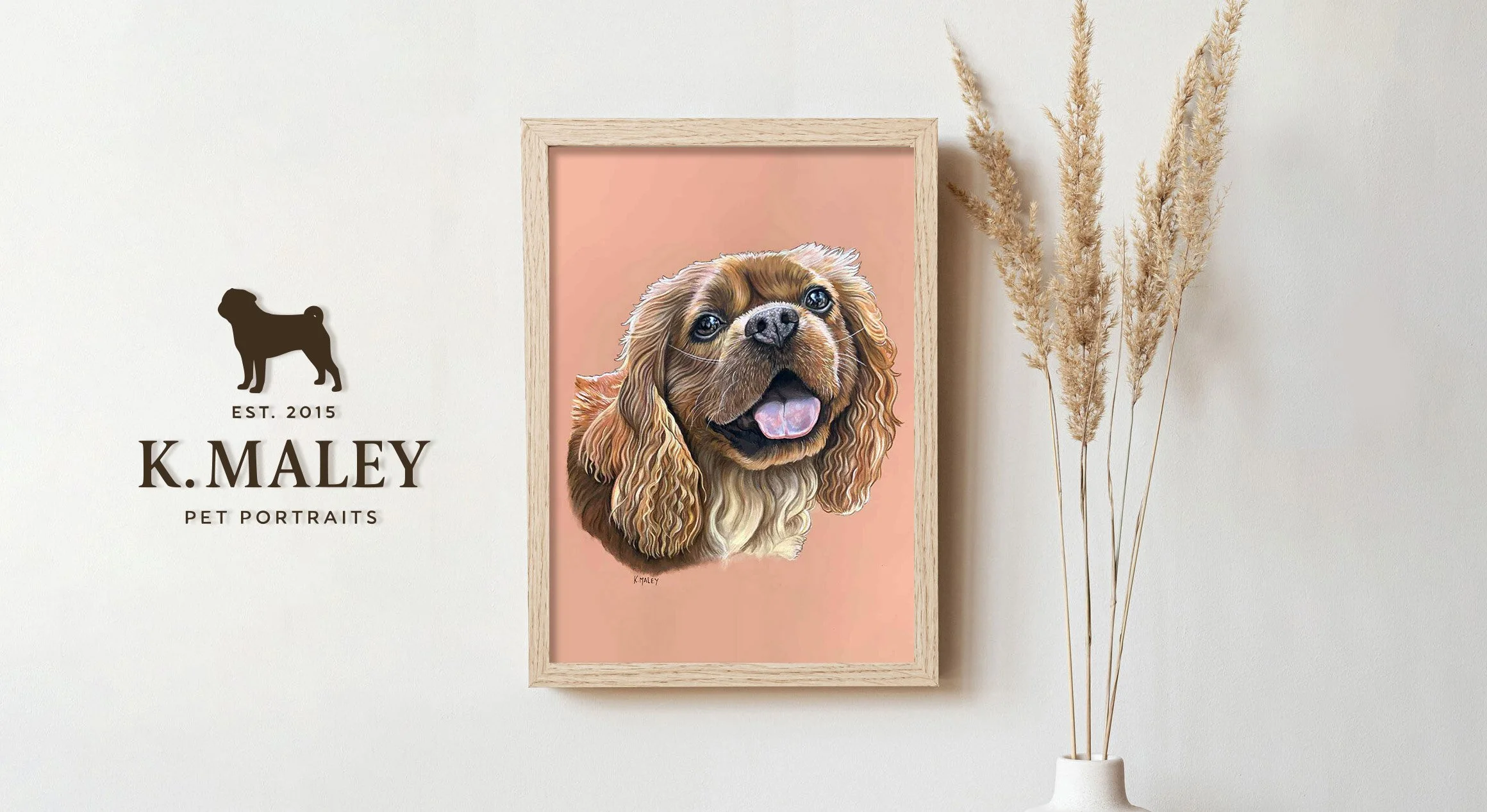 A pet portrait of a brown dog with long curly ears, framed and hung on a wall next to a vase with pampas grass, with text indicating it is by K. Maley, established 2015.