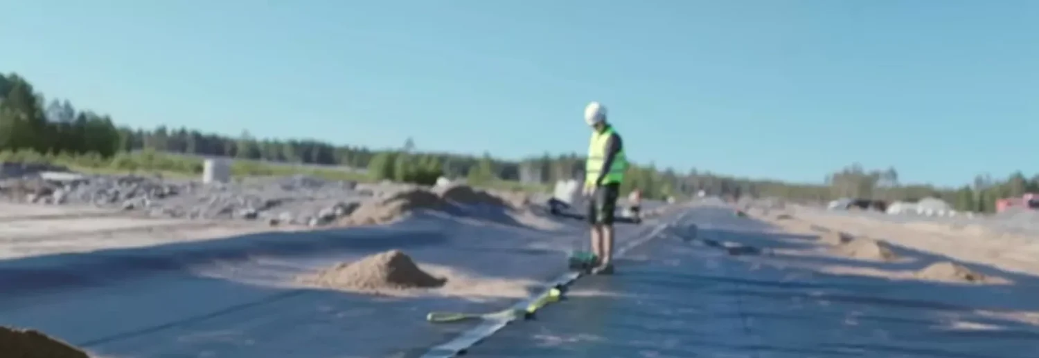 Montör som svetsar en fog i geomembran med svetsmaskin på plats