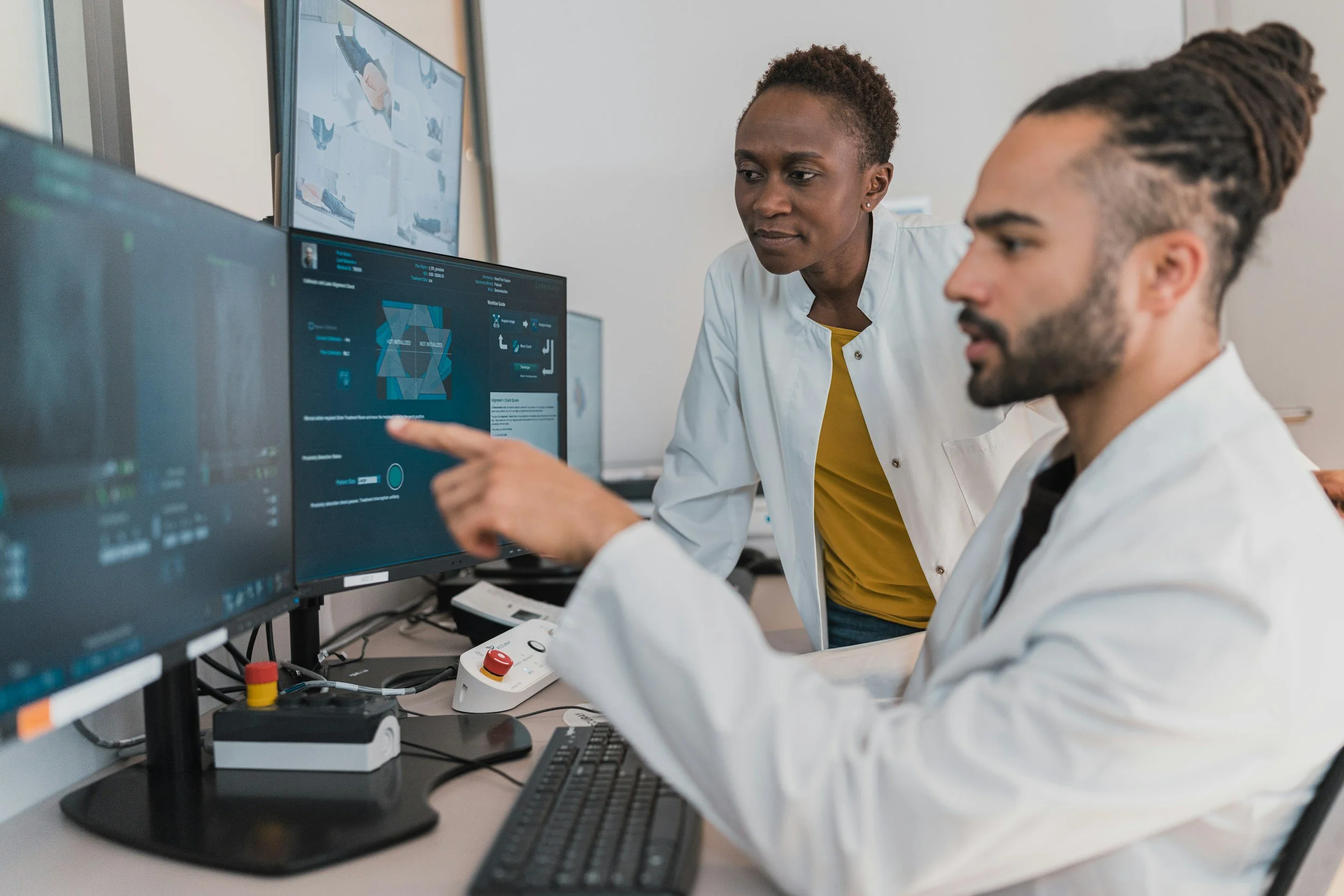 Two scientists, a woman and a man, analyzing data on computer screens in a laboratory.