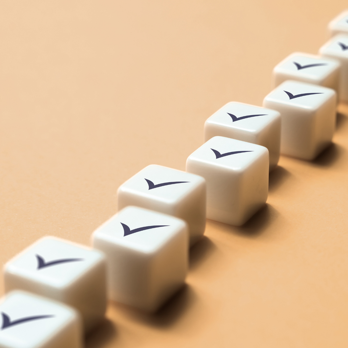 A row of white dice with check marks on the top face, arranged diagonally on a beige surface.