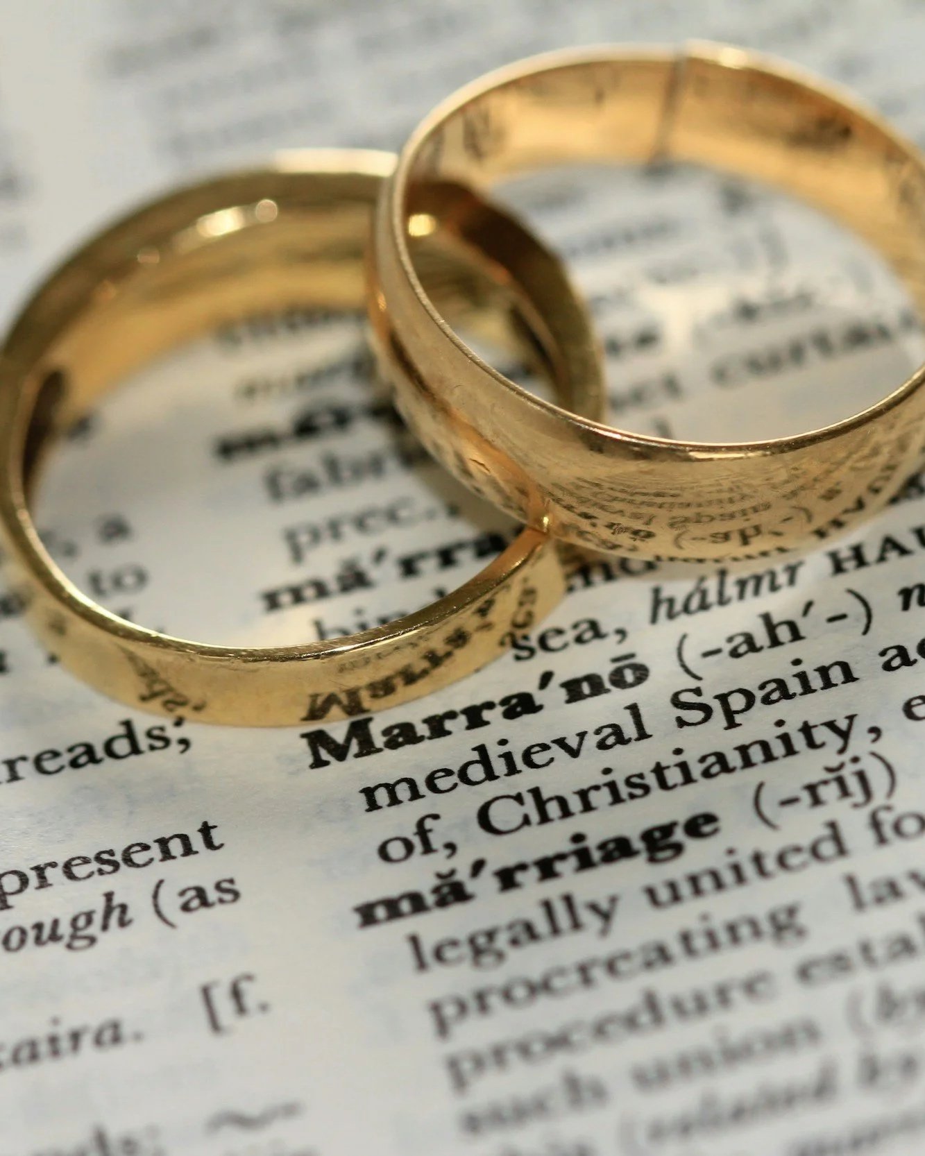 Dos anillos dorados sobre un libro abierto con texto en inglés.