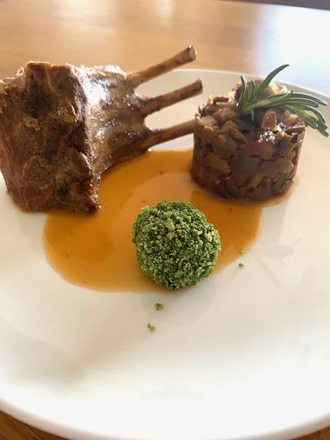 A plated gourmet lamb chop with sauce, a broccoli floret, with ratatouille picked for one of my clients with a meat menu at Roland Paix catering.