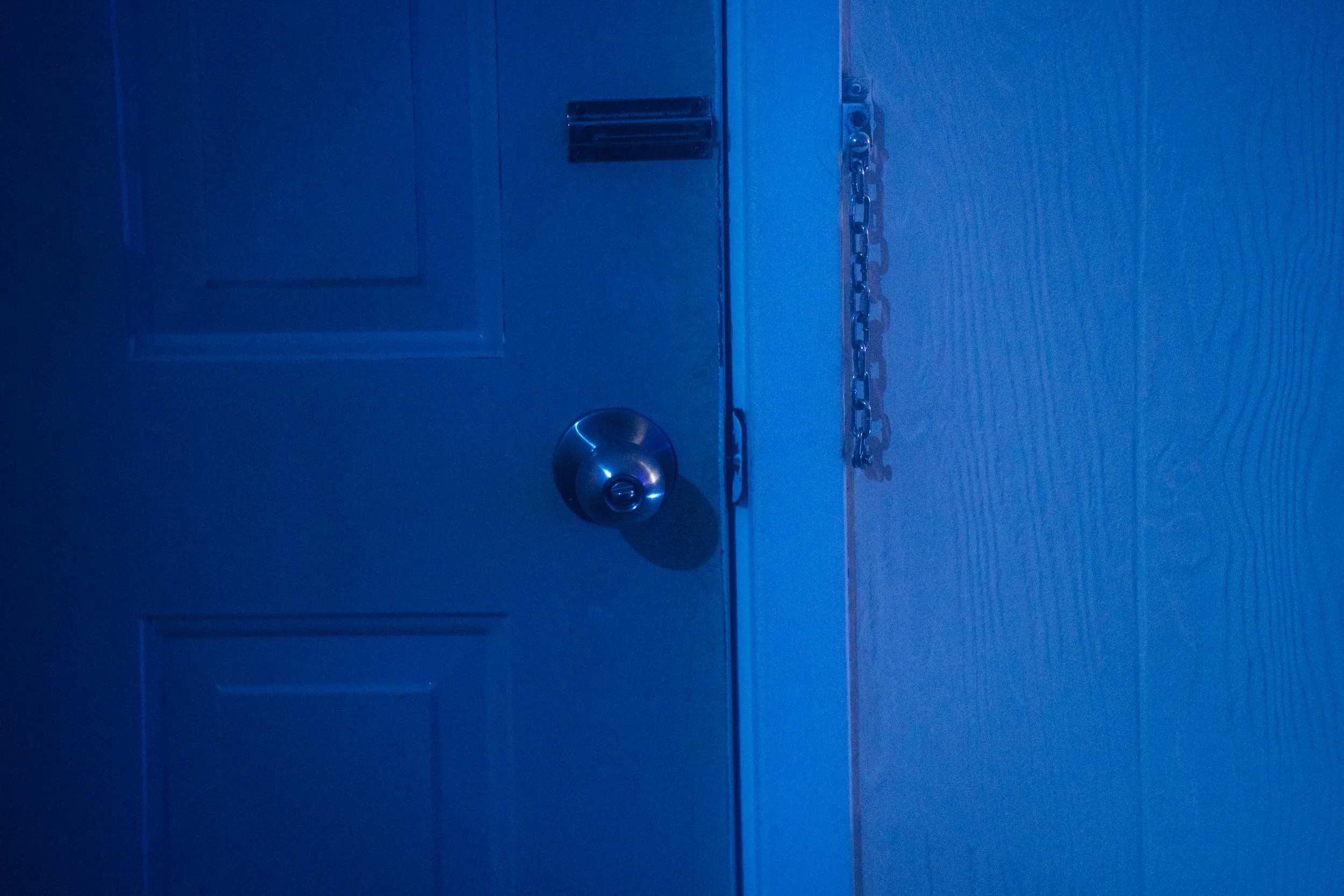 Une porte bleue avec un verrou, une poignée et une chaîne