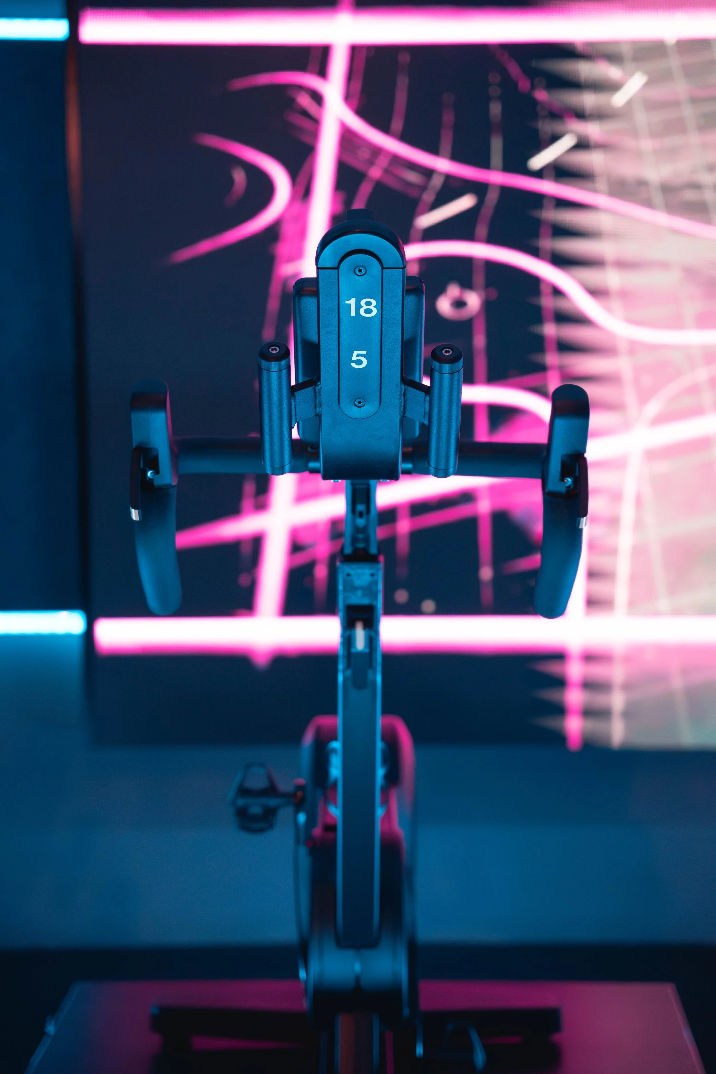 Een fiets onder neonlichten met roze en blauwe kleuren in een donkere ruimte.