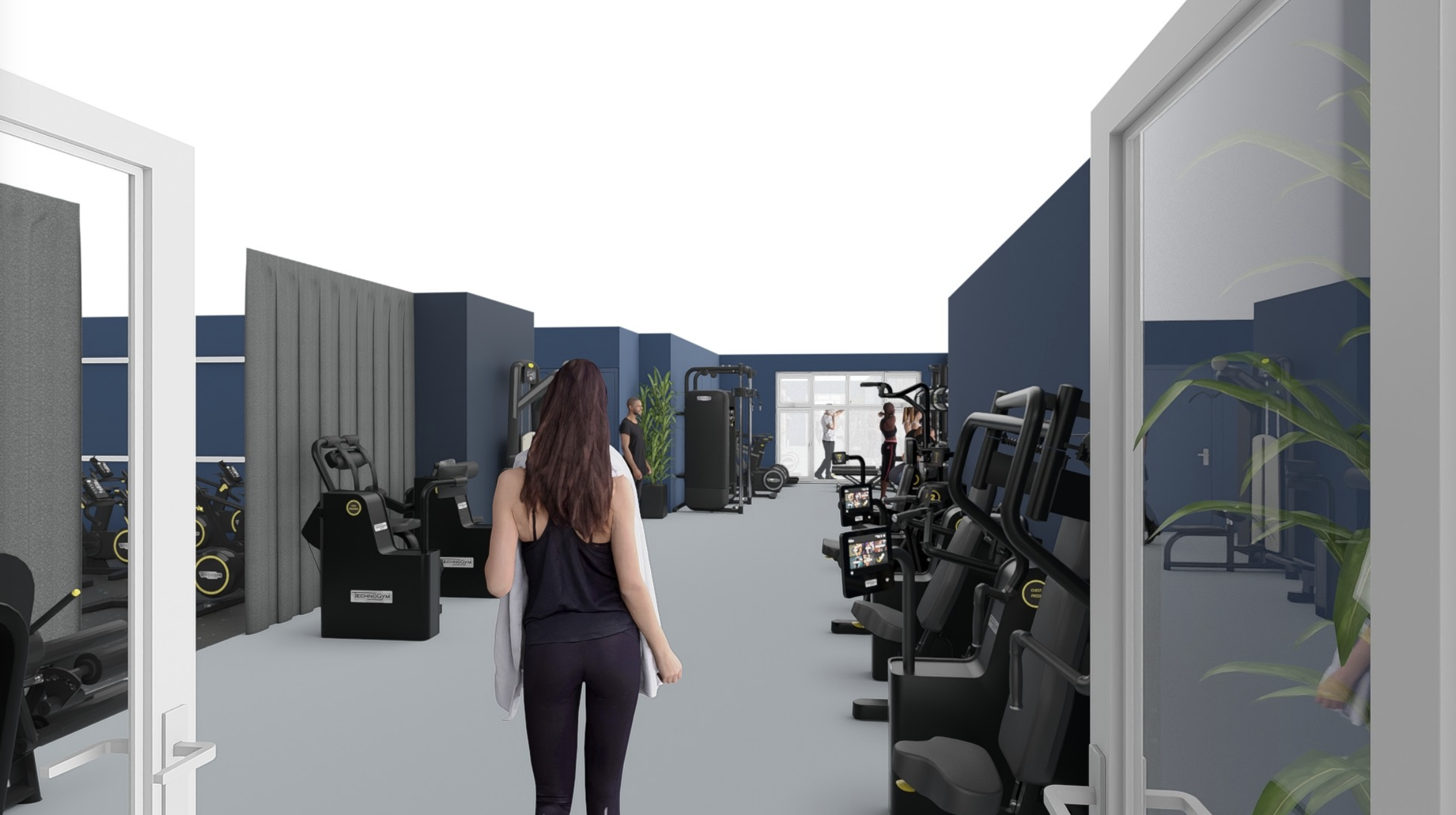 Binnenzicht van een fitnessruimte met verschillende cardio- en krachtapparaten, mensen die trainen en een vrouw die de ruimte binnenloopt.