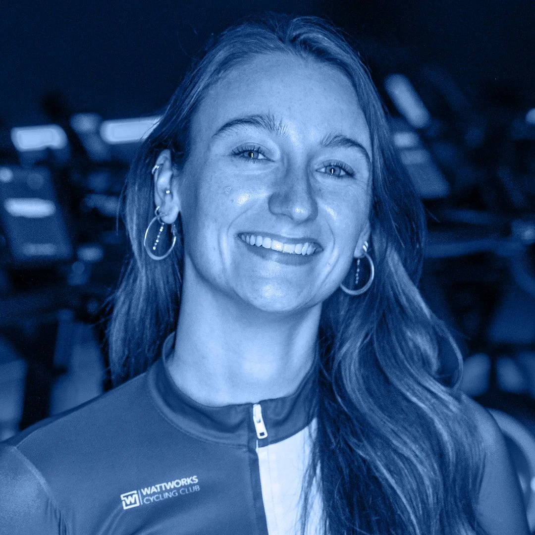 Vrouw in wielrenoutfit met WATTWORKS Cycling Club logo, glimlachend, sportieve uitstraling.