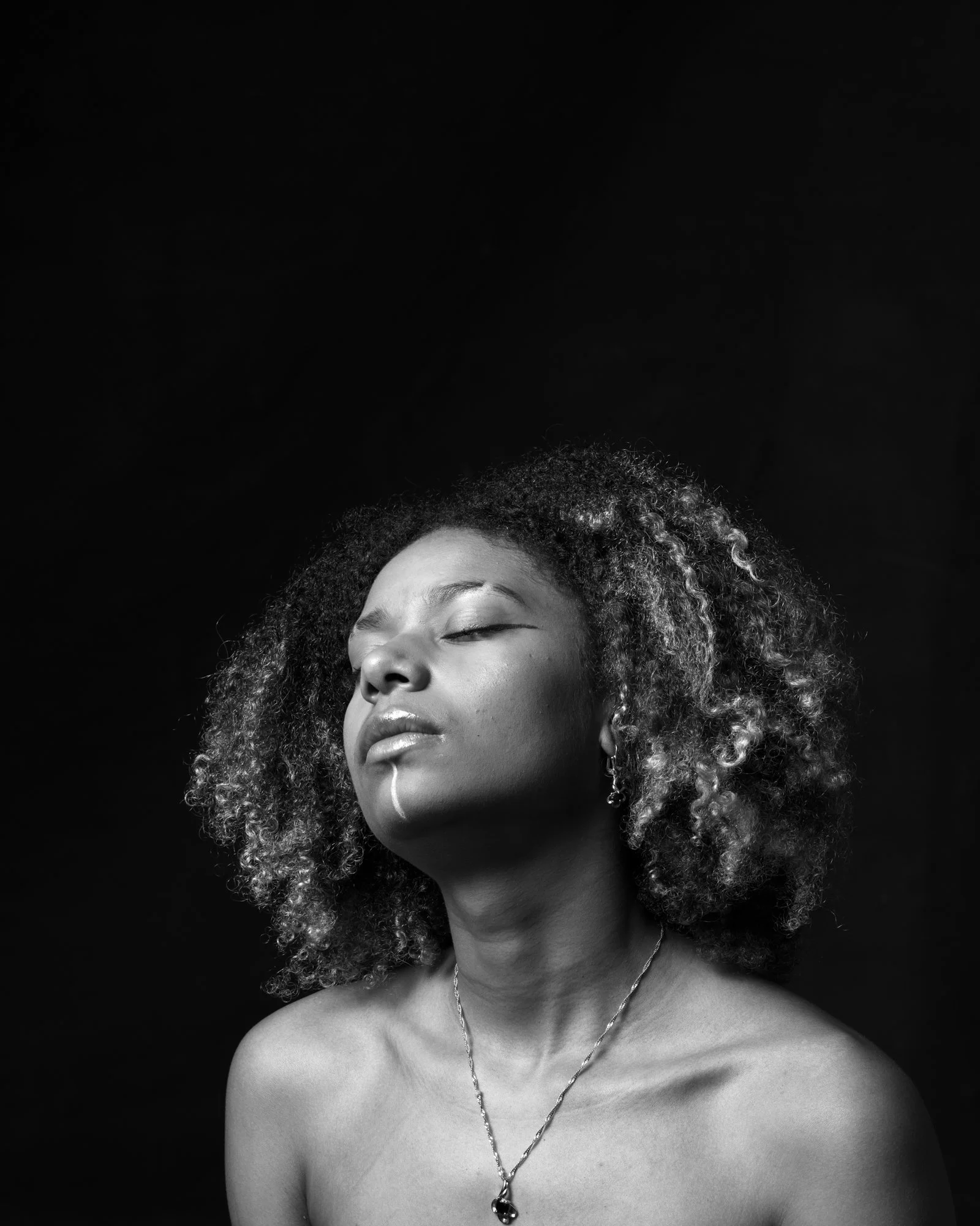 Evocative portrait of a figure shrouded in shadow, appearing from a soft light beam.