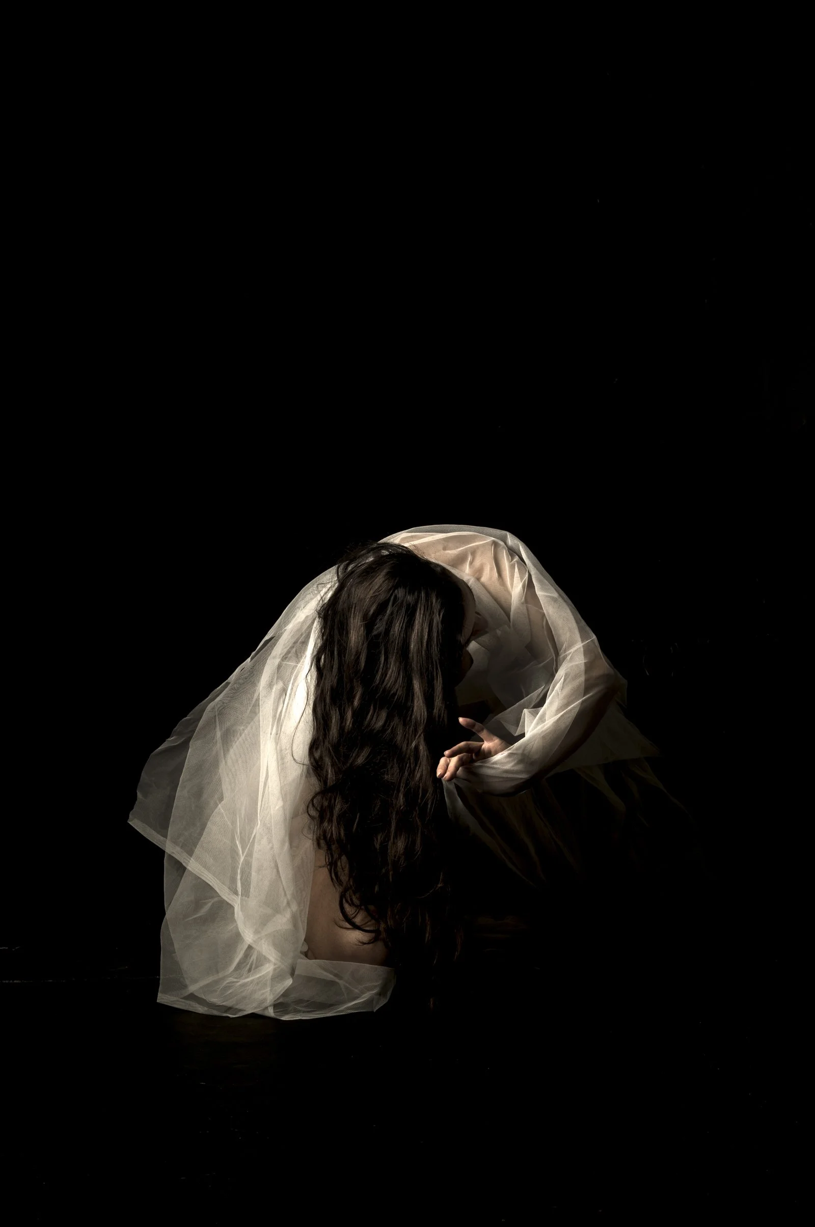 Minimalist fine art portrait featuring dramatic light and shadow on a red fabric drape.
