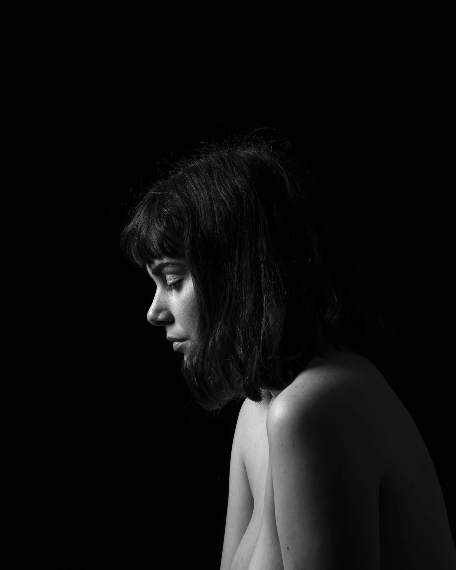 Soft light on a subject's face contrasting with a solid, absolute black background.