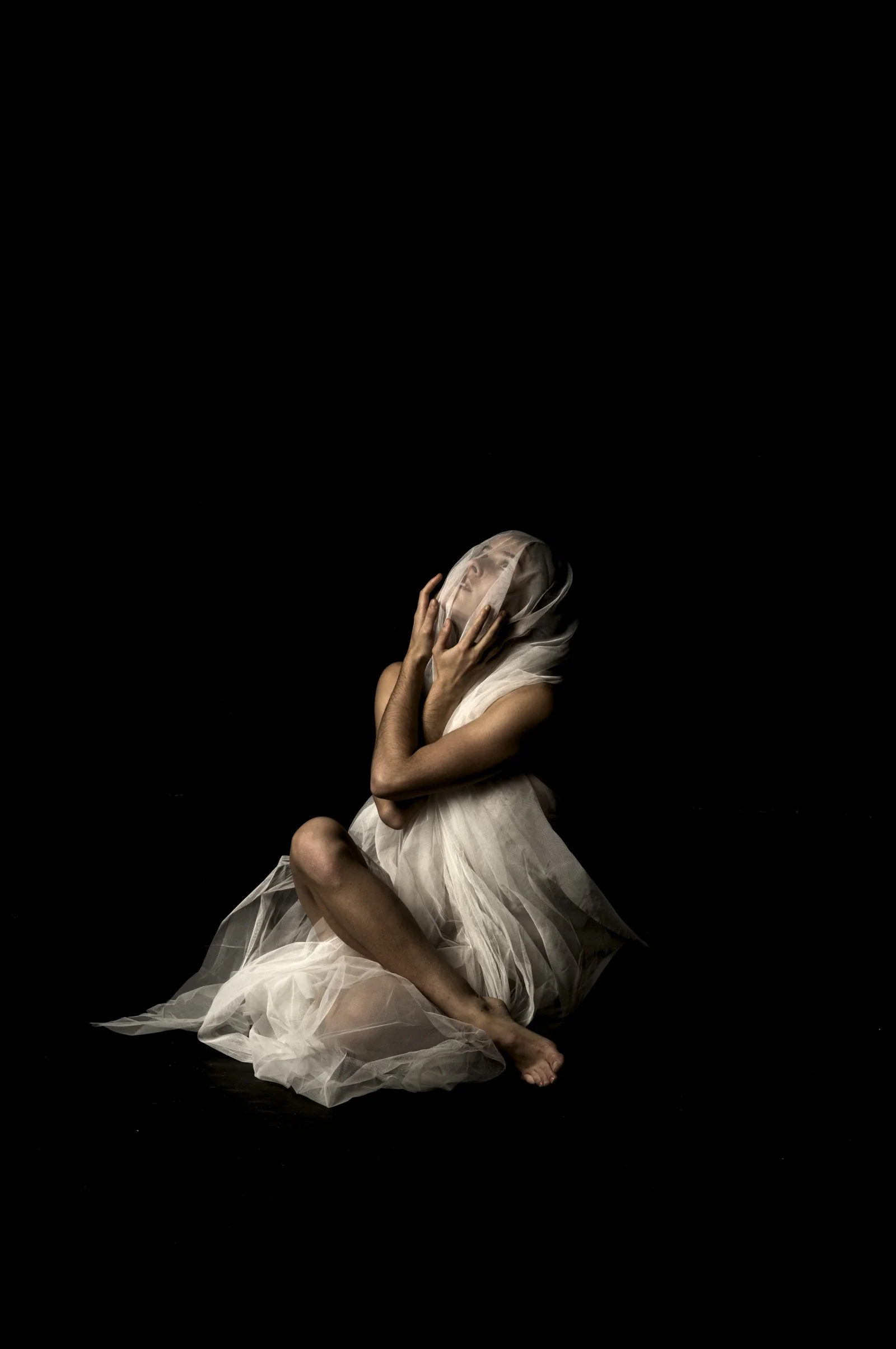 The human form partially hidden by a white fabric, capturing a sense of quiet intensity.