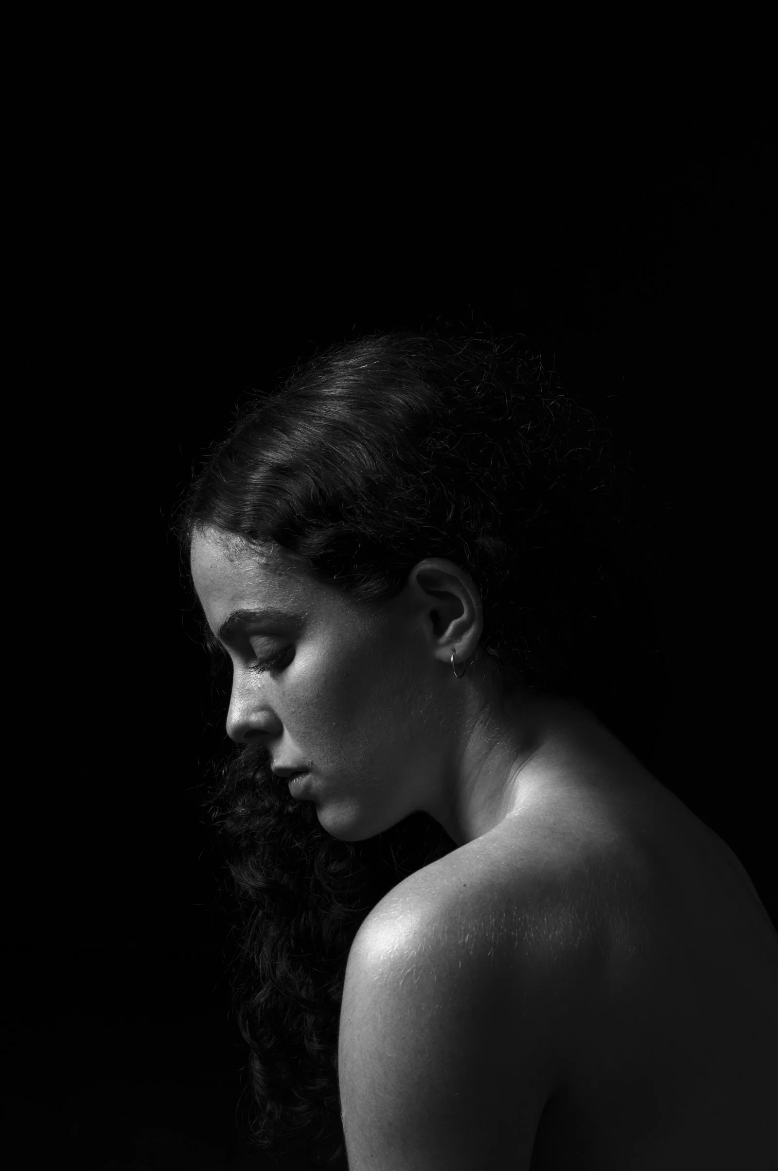 Fine art portrait focused on the subject's silhouette against an absolute black background.