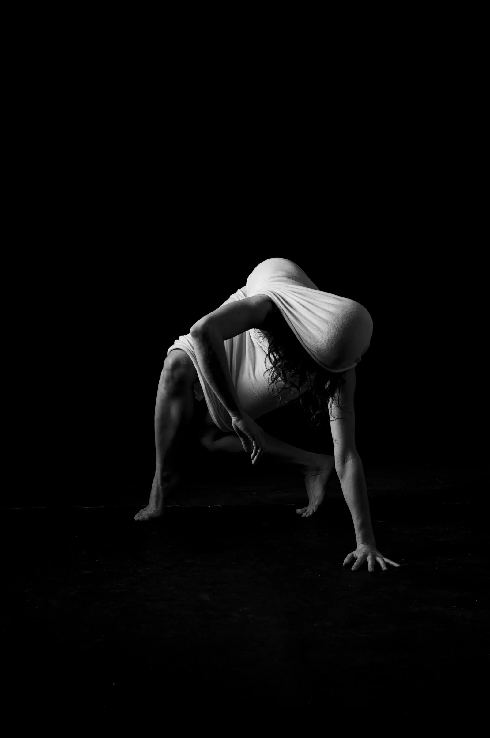 Abstract figure study where dramatic light and shadow transform the body into organic shapes.