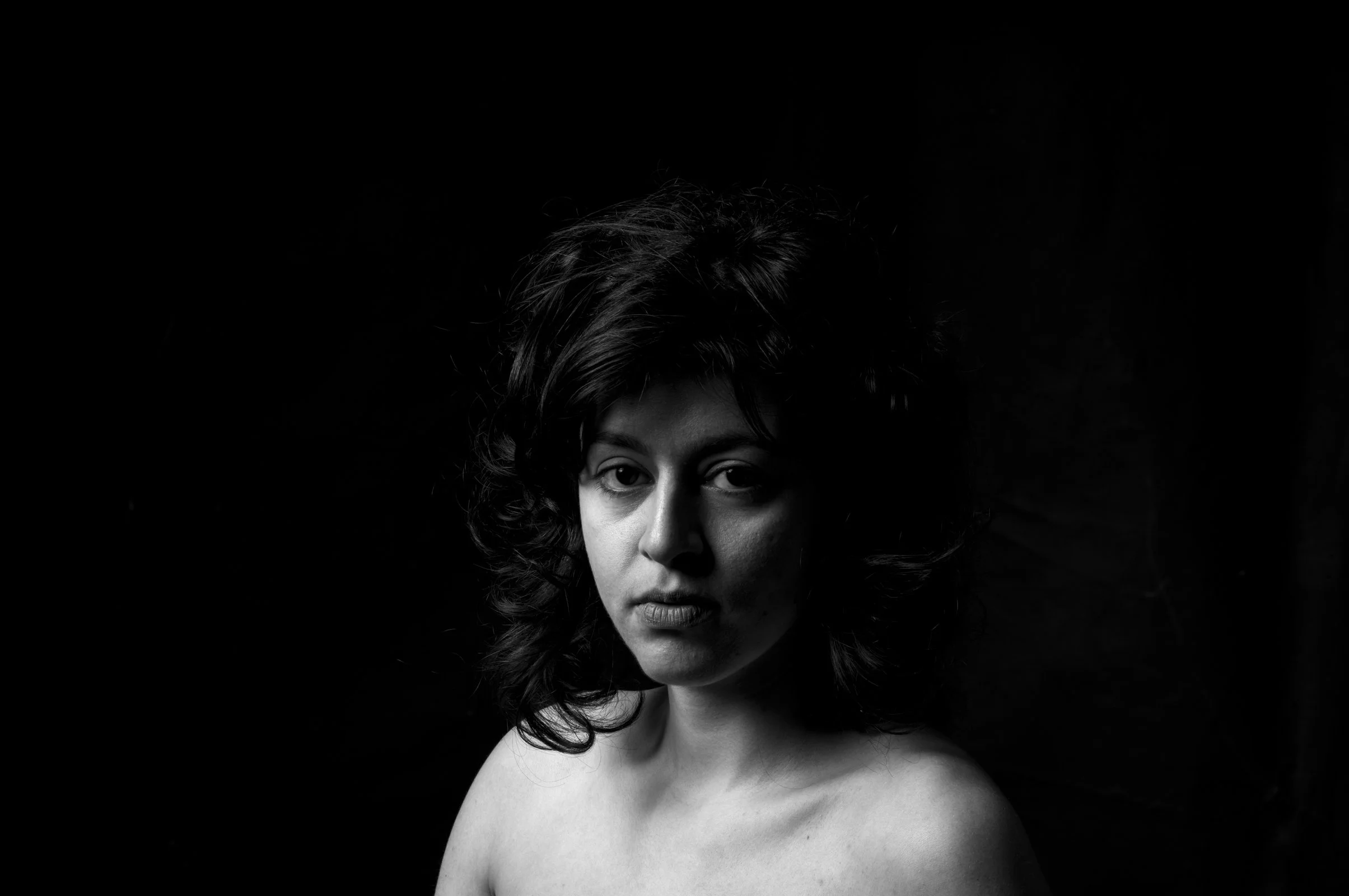 High-contrast black and white portrait featuring soft rim lighting on a person's profile.