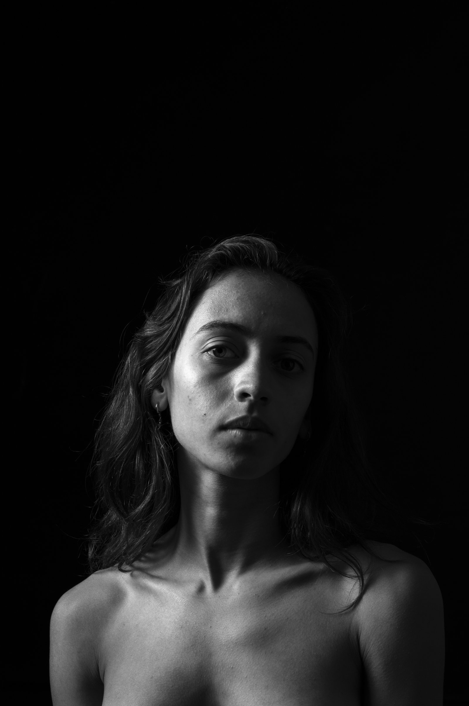 Detailed view of dramatic highlights tracing a person's shoulder in a dark studio setting.