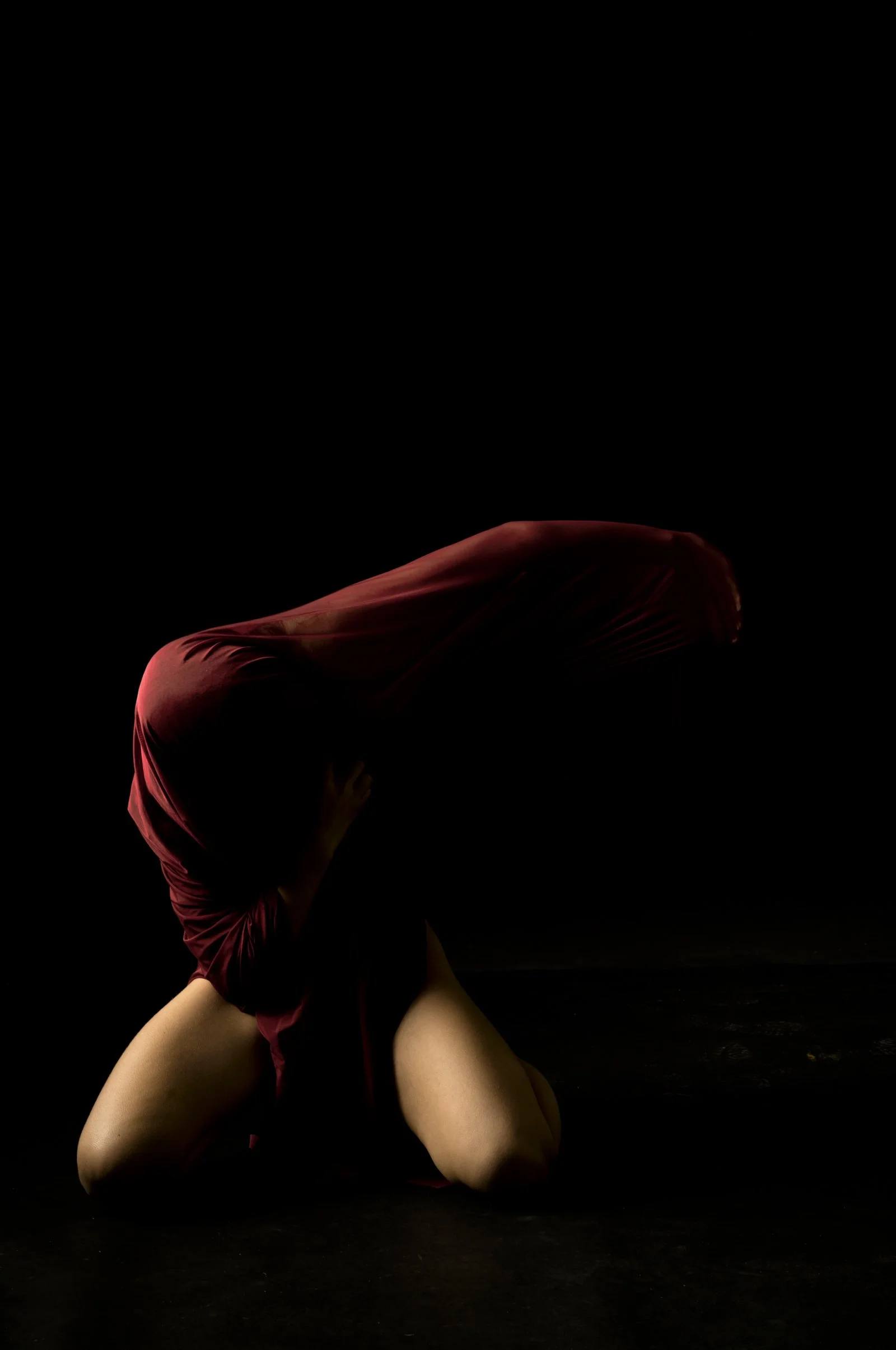 Artistic study of light hitting a red drape in a dark, minimalist setting.