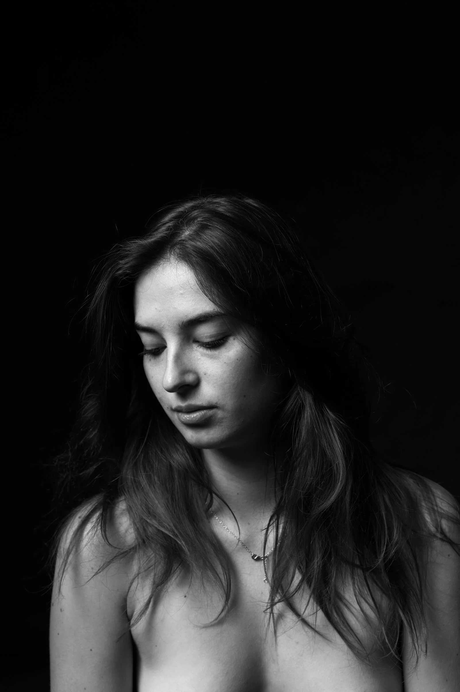 Minimalist portrait with a person gazing downward, evoking a sense of quiet intensity.