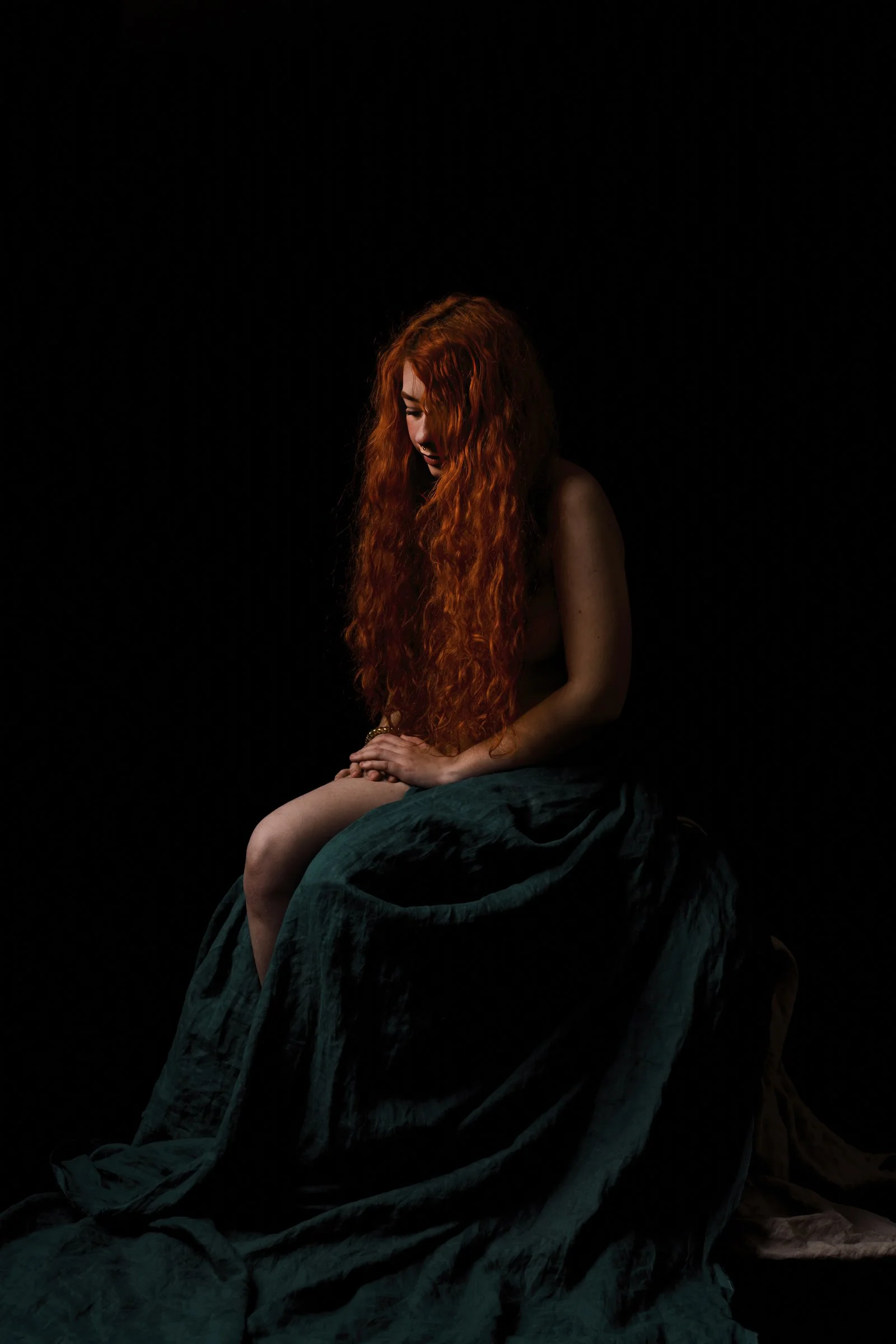 Minimalist portrait with a subject emerging from absolute darkness into a soft, focused light beam.