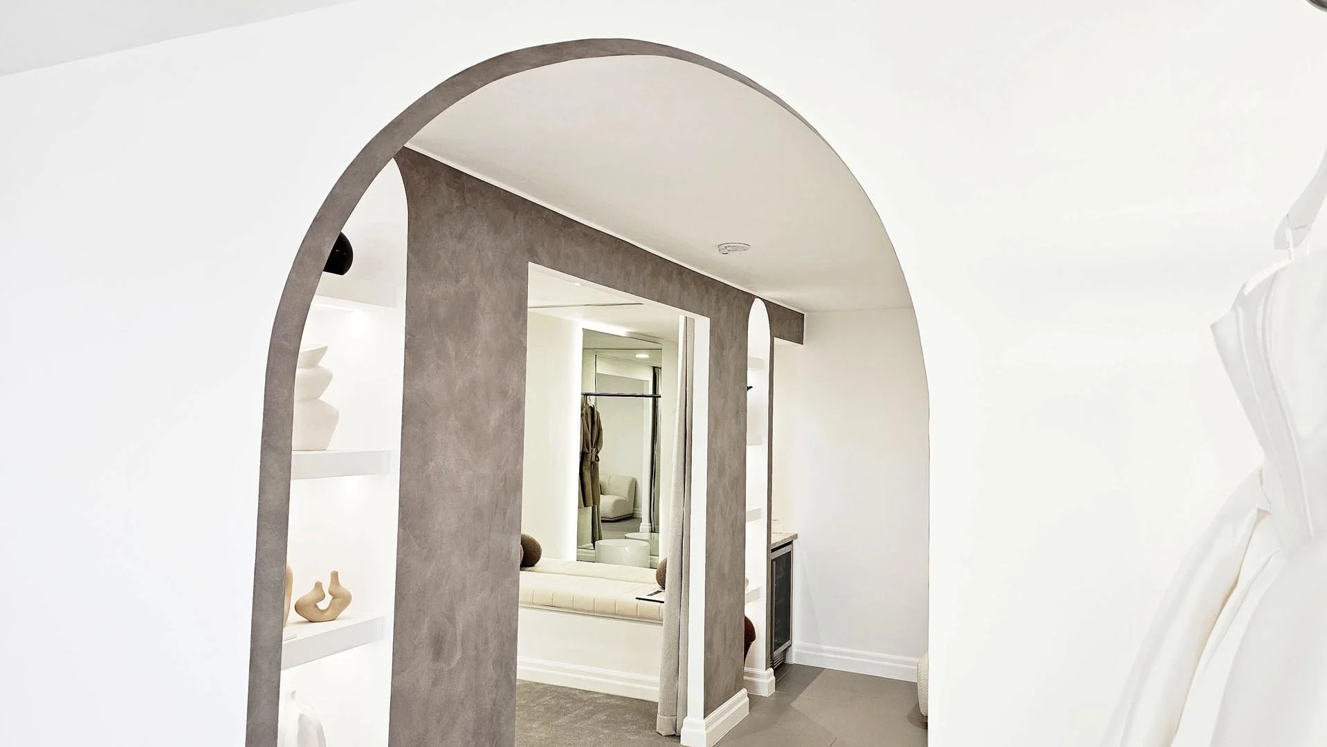 Modern interior view of a home with an arched doorway leading to a sitting area with a window seat and neutral decor.