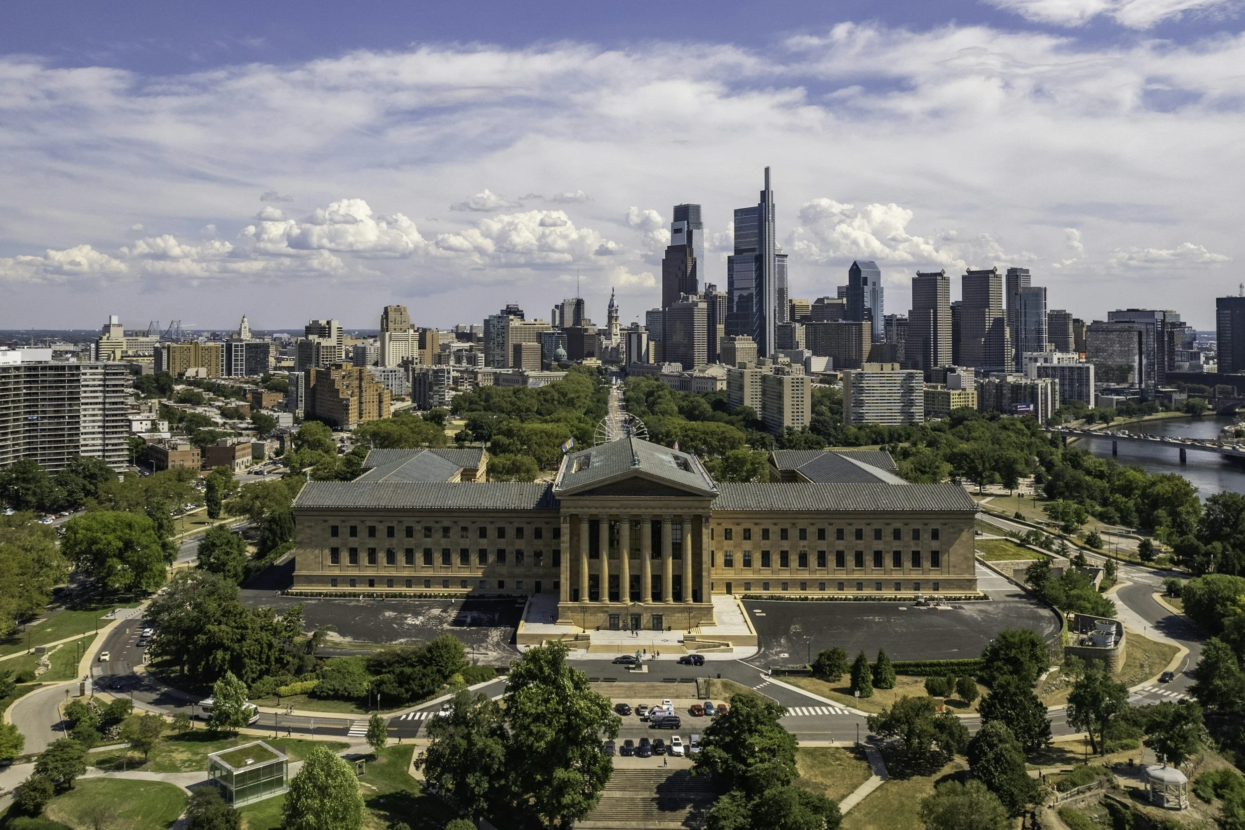 An aerial view of Philadelphia's Benjamin Franklin Parkway with the Philadelphia Museum of Art in the foreground and the Philadelphia skyline in the background.