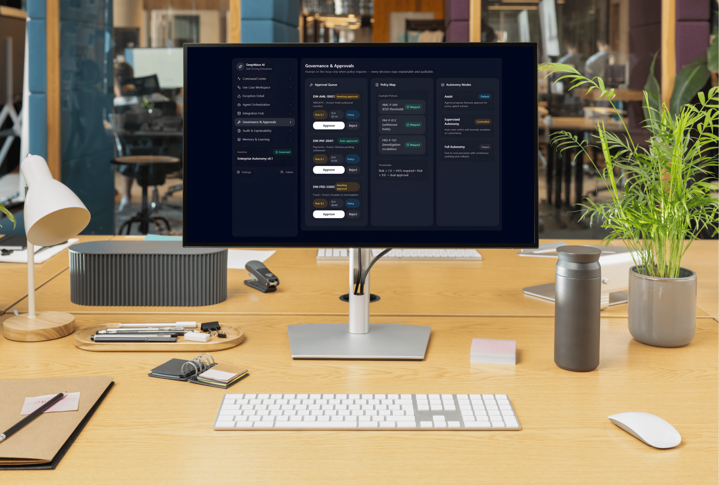Computer monitor on a wooden office desk displaying a governance and approvals interface. The desk has a keyboard, mouse, notebooks, pens, a water bottle, small plants, and office supplies. In the background, there are other office spaces with desks and chairs.