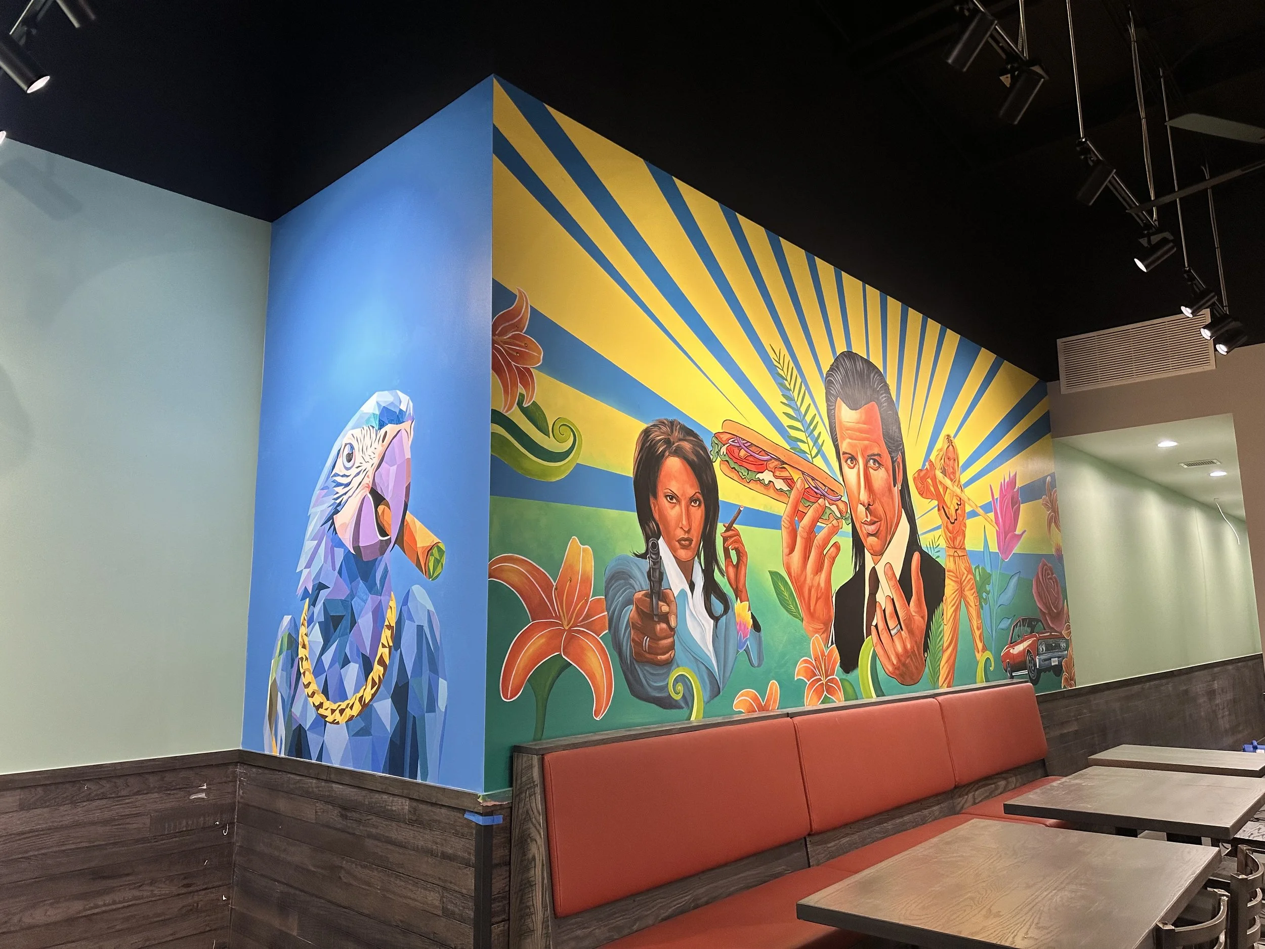 Colorful mural featuring stylized illustrations of a parrot, a woman pointing a gun, a man holding a sandwich, and a woman with a bow and arrow, surrounded by flowers, a car, and vibrant rays in the background.