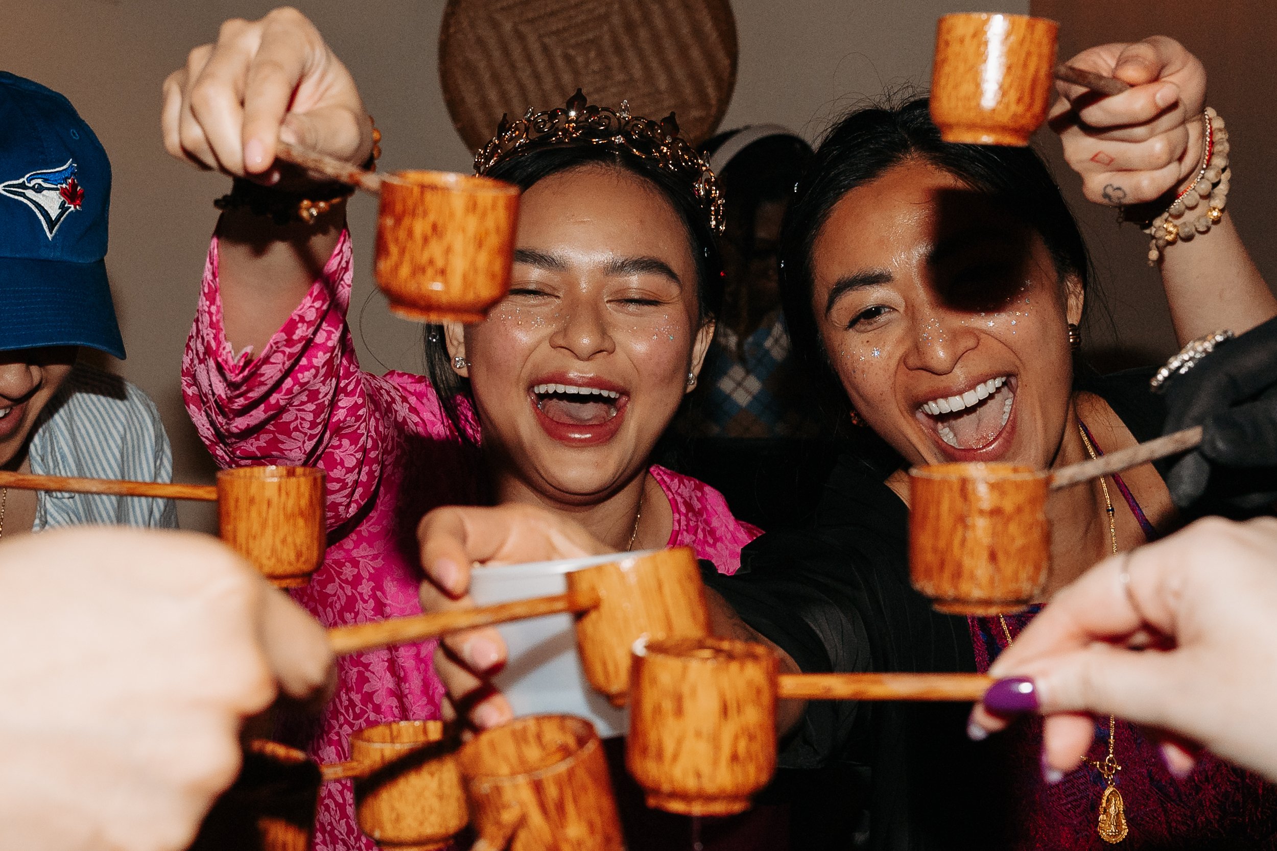 People smiling and toasting with wooden cups at a celebration.