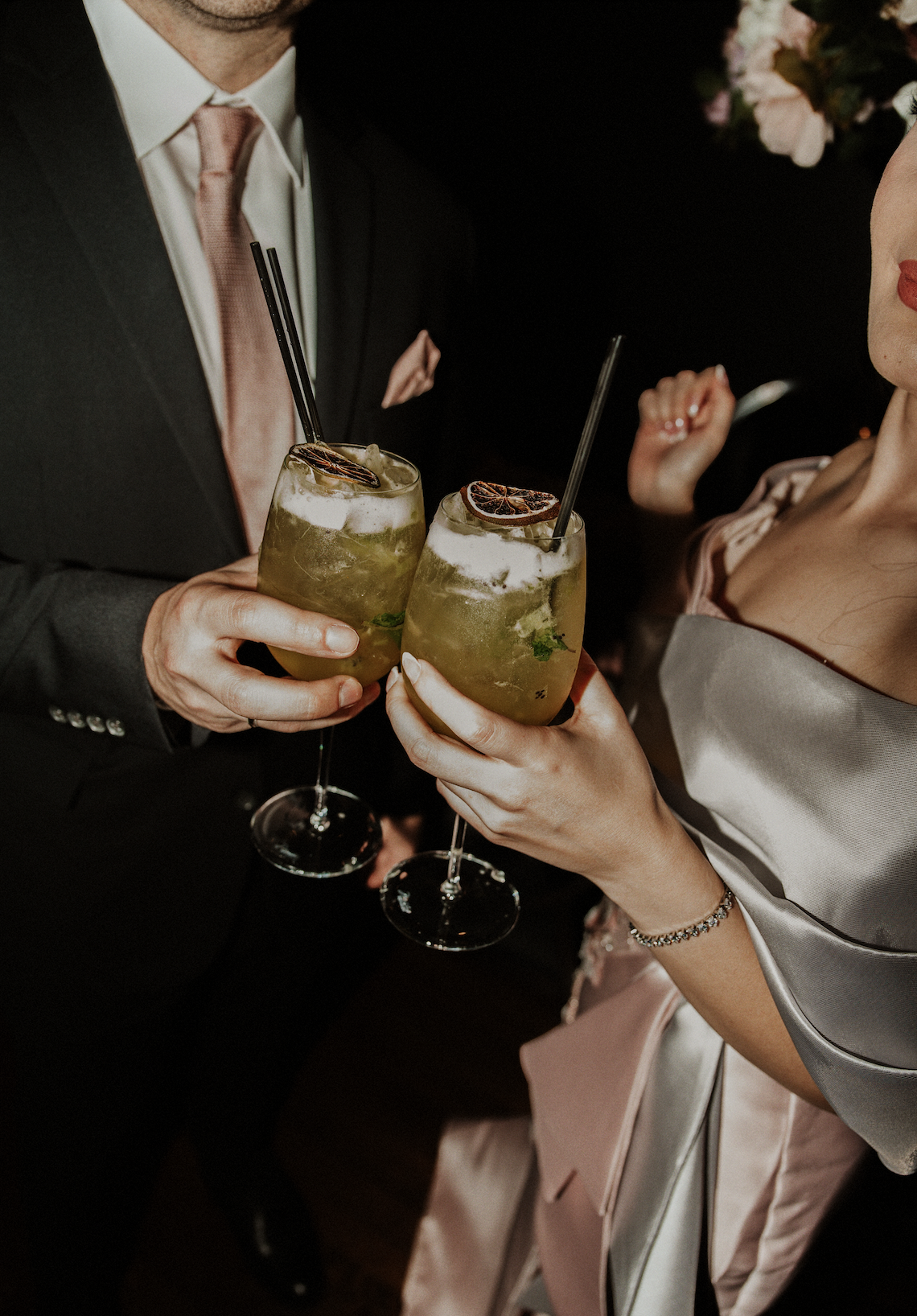 Two people holding cocktails with lemon slices at a celebration or party.