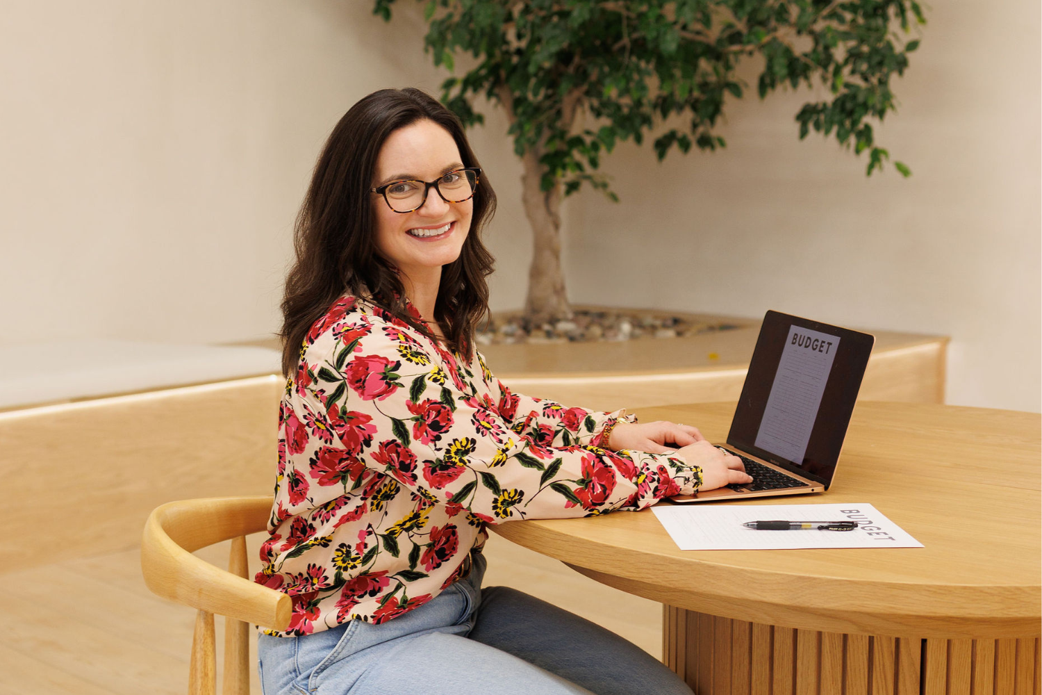 Alaina Trivax, author of Follow the Money: A Fun Financial Literacy Game for Kids, typing on computer with a budget in front of her