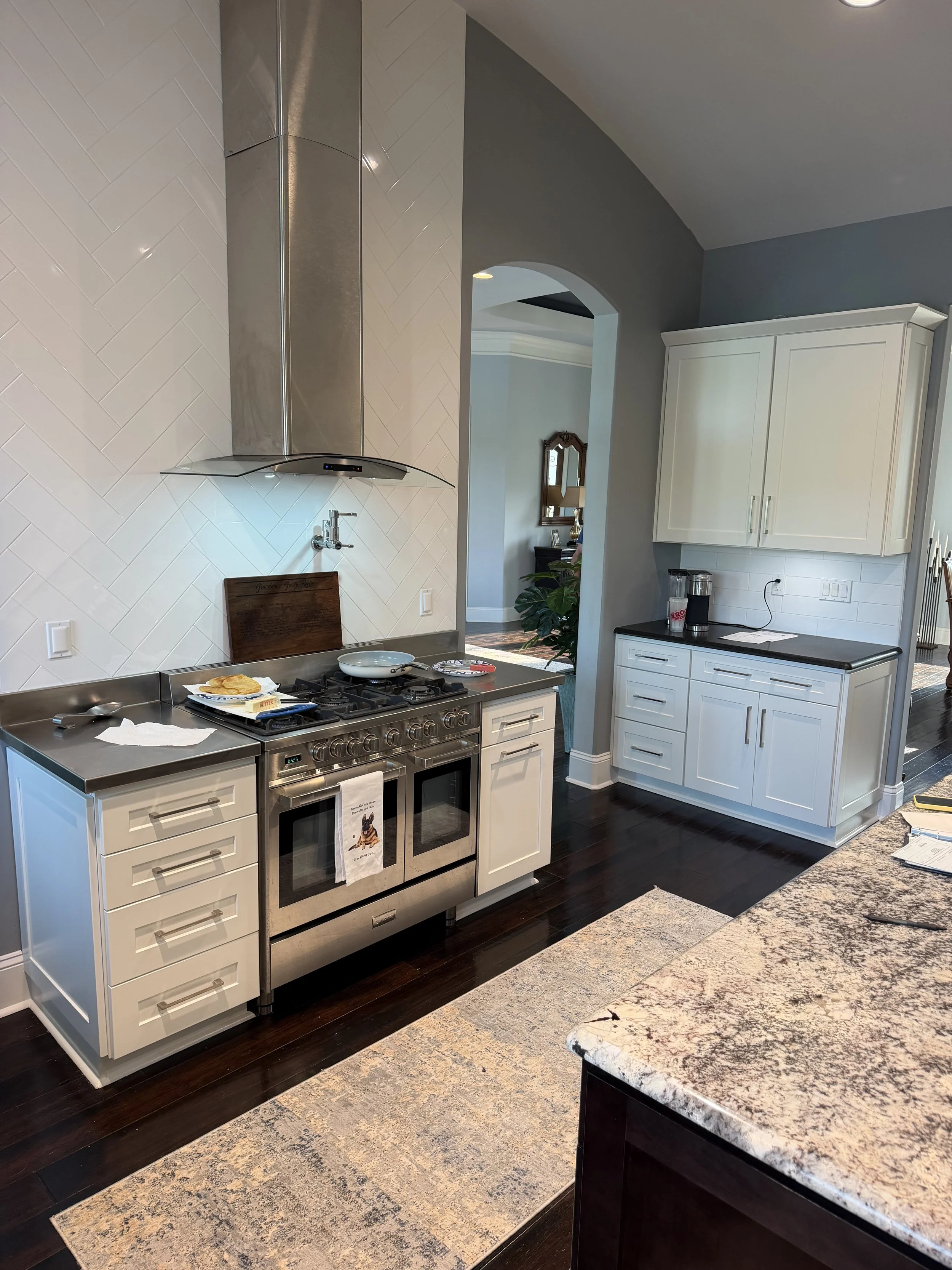 Completed kitchen cabinet refinishing with white cabinets and contrasting countertops