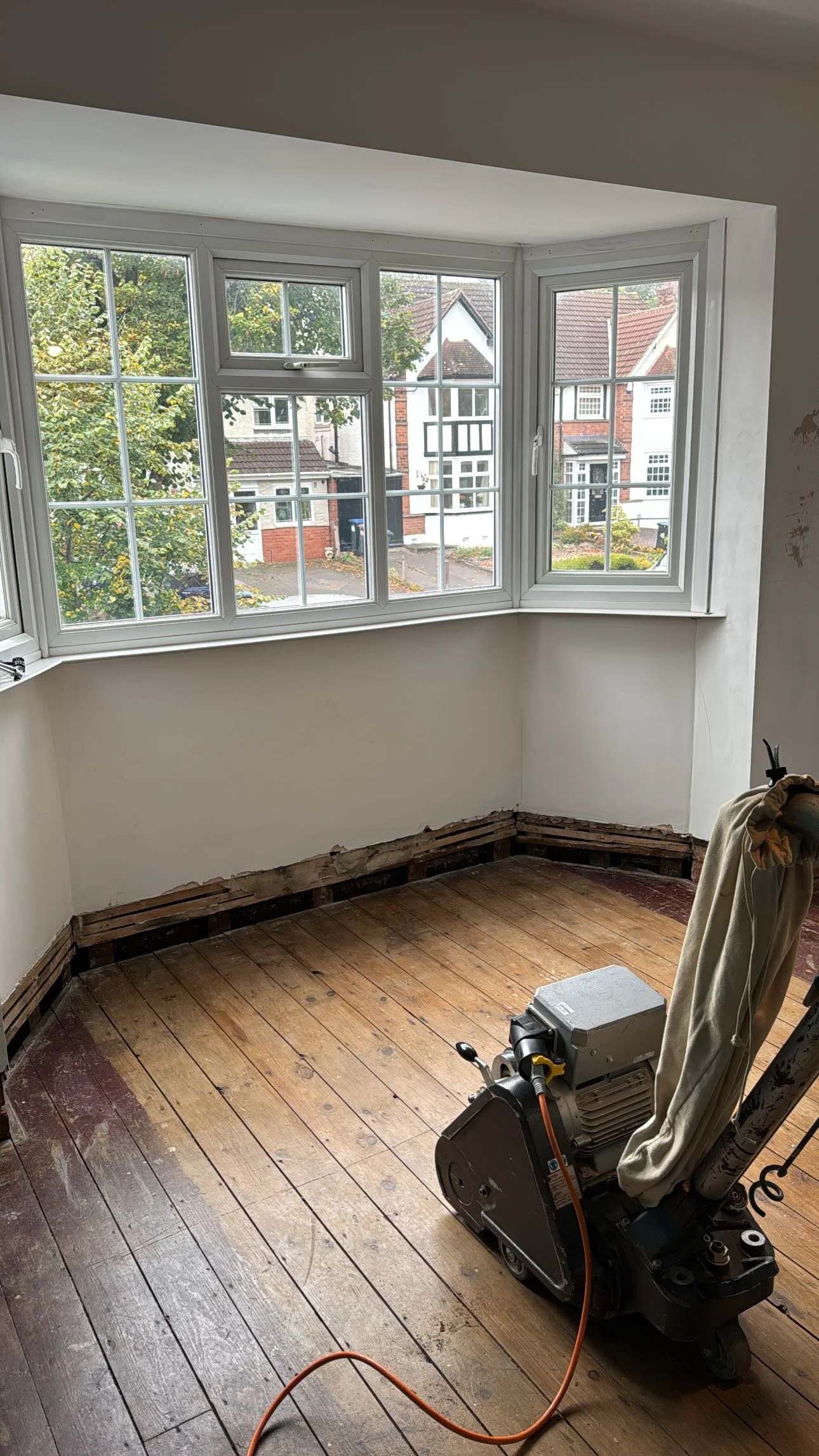 Pine wood floorboards before sanding, showing belt sander preparation during floor restoration in Birmingham, West Midlands.