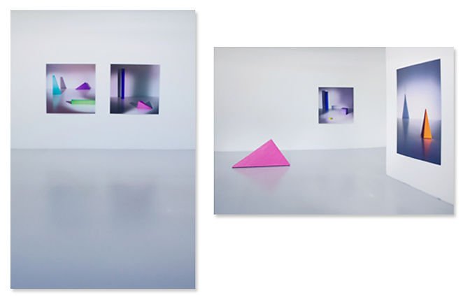 Contemporary art exhibition featuring colorful geometric sculptures and framed artworks in a minimalist white gallery space.