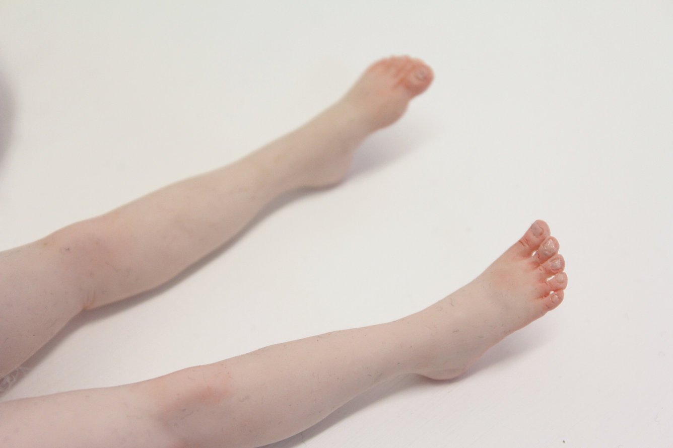 Two human legs stretched out on a white surface, with one leg with foot slightly raised.