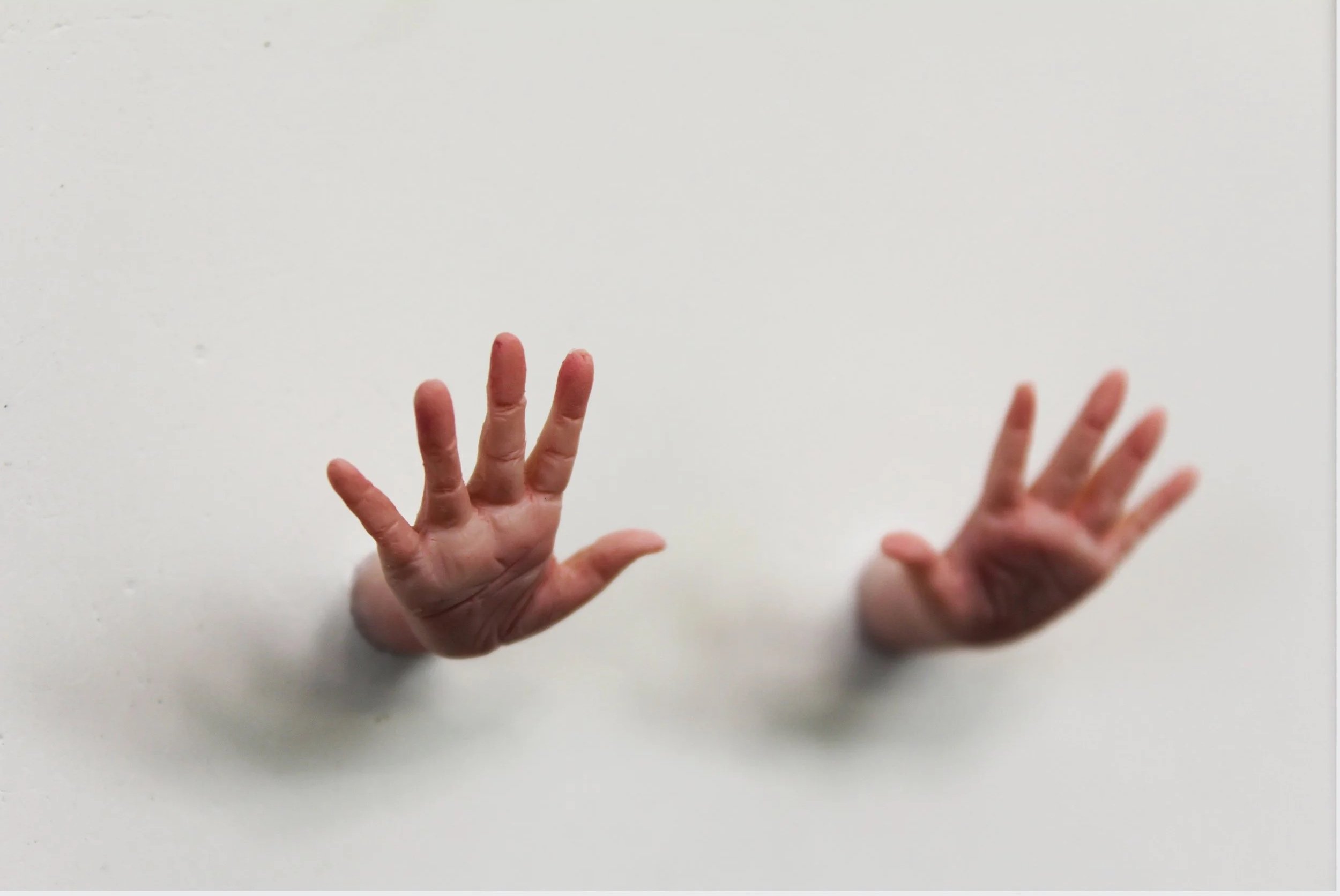 Two disembodied human hands reaching upward against a plain white background.