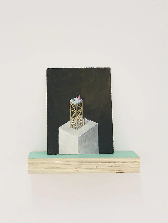 A small sculpture of a wooden tower with a pink cone on top, situated on a white square platform against a black background, with a teal and wooden shelf beneath.