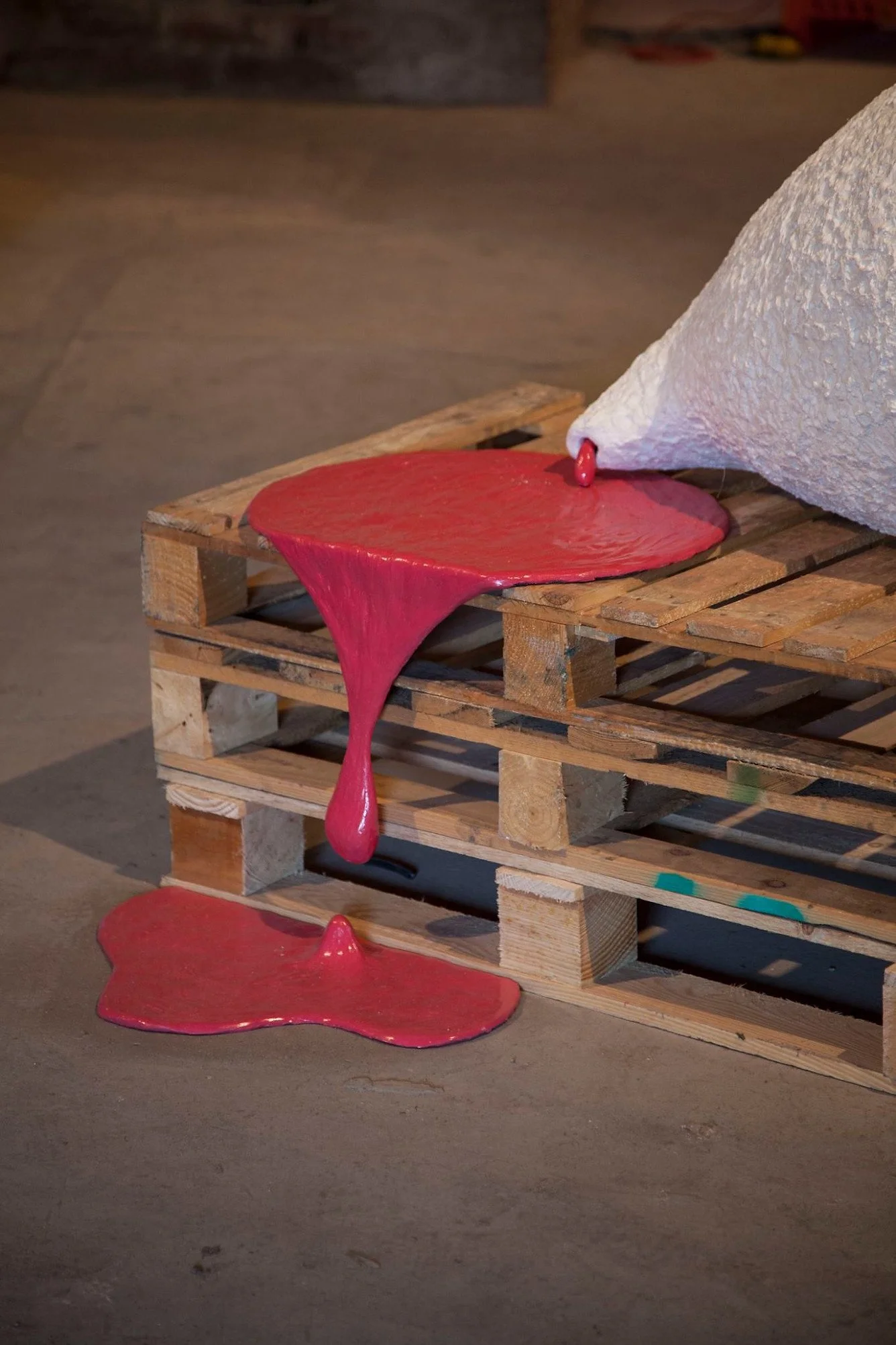 A wooden pallet with red, melted-looking material spilling over and dripping down.
