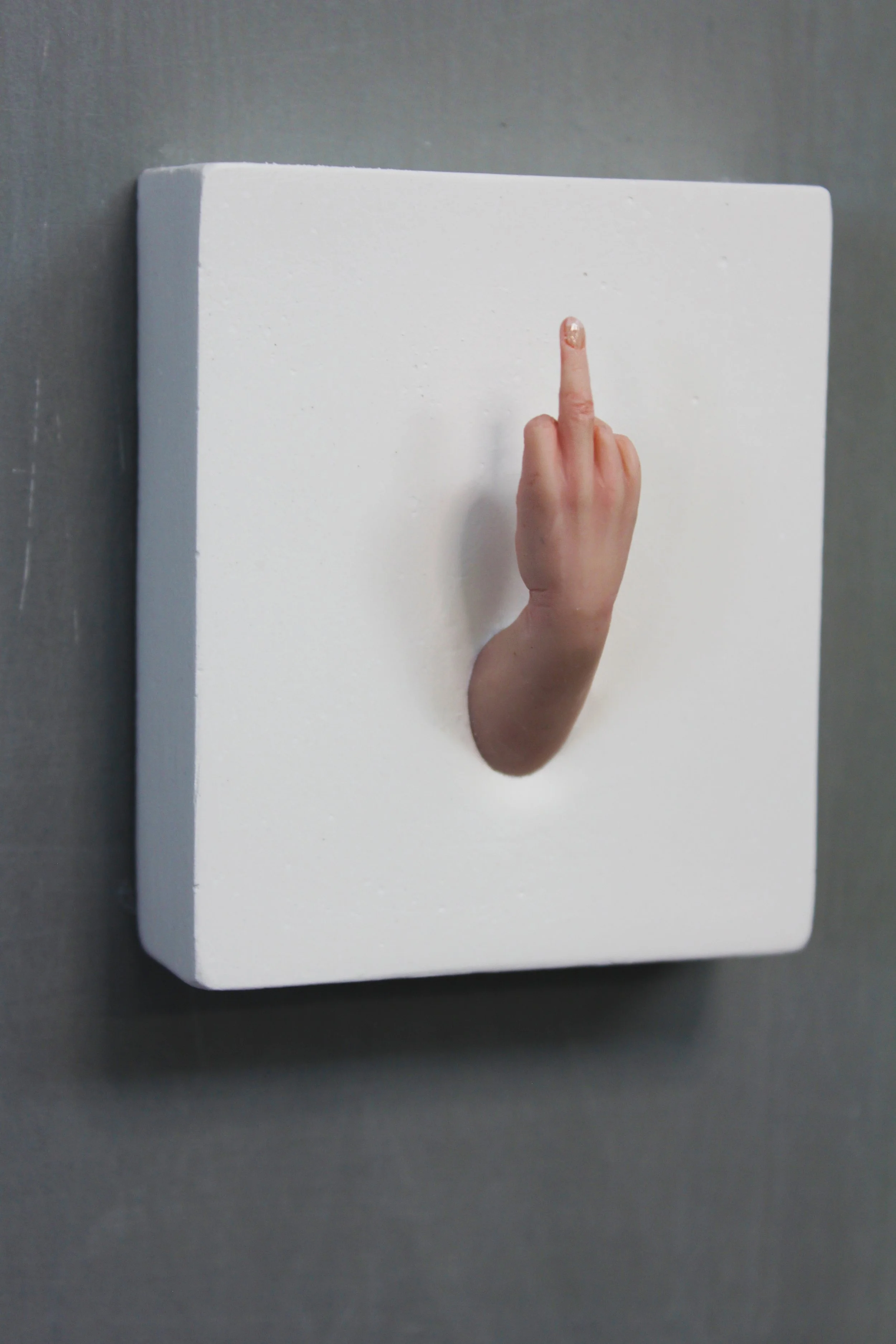 A white 3D wall art piece shaped like a human finger.