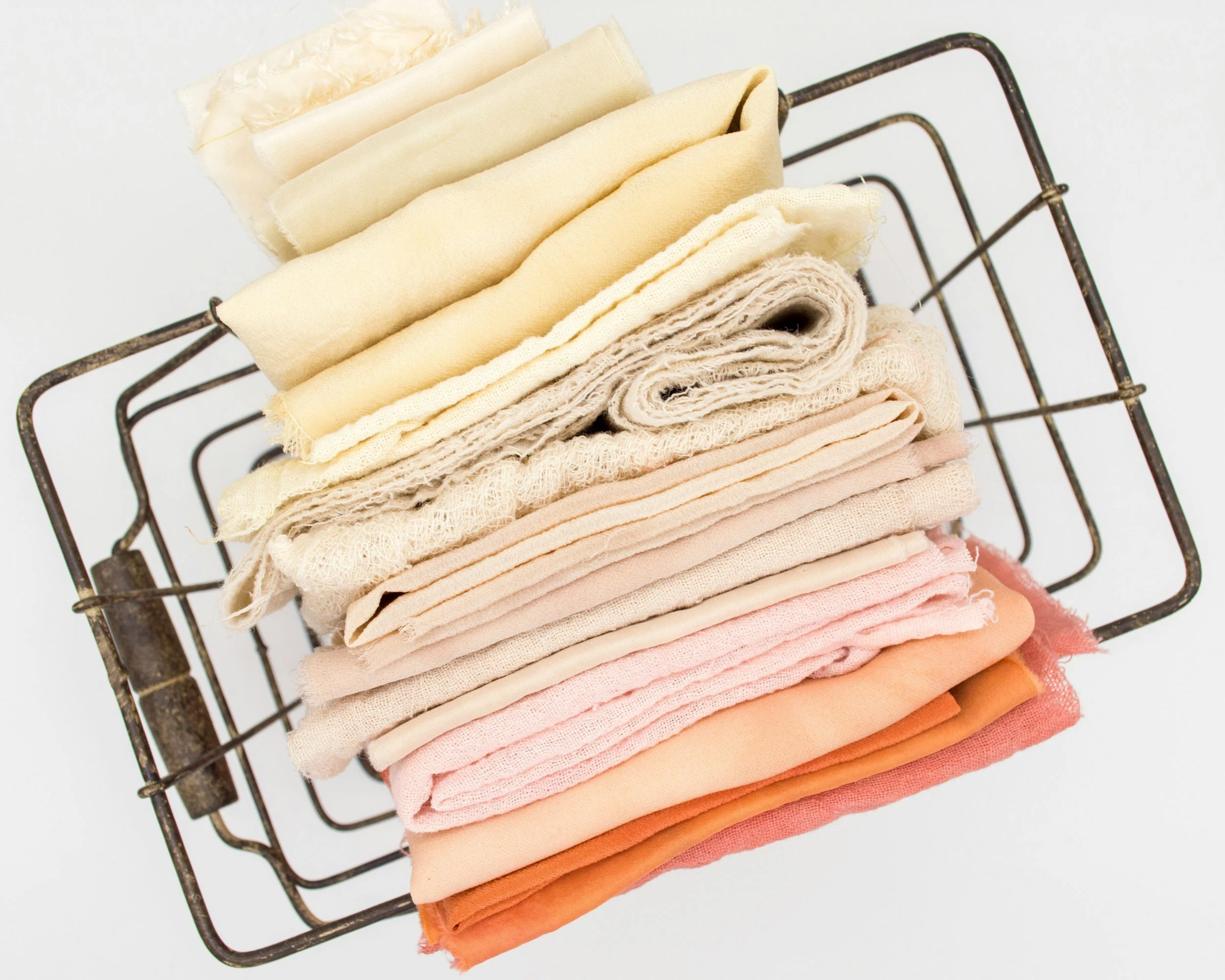 Stack of pastel-colored fabrics on a metal rack.