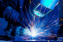 A person welding metal with sparks flying in a workshop.