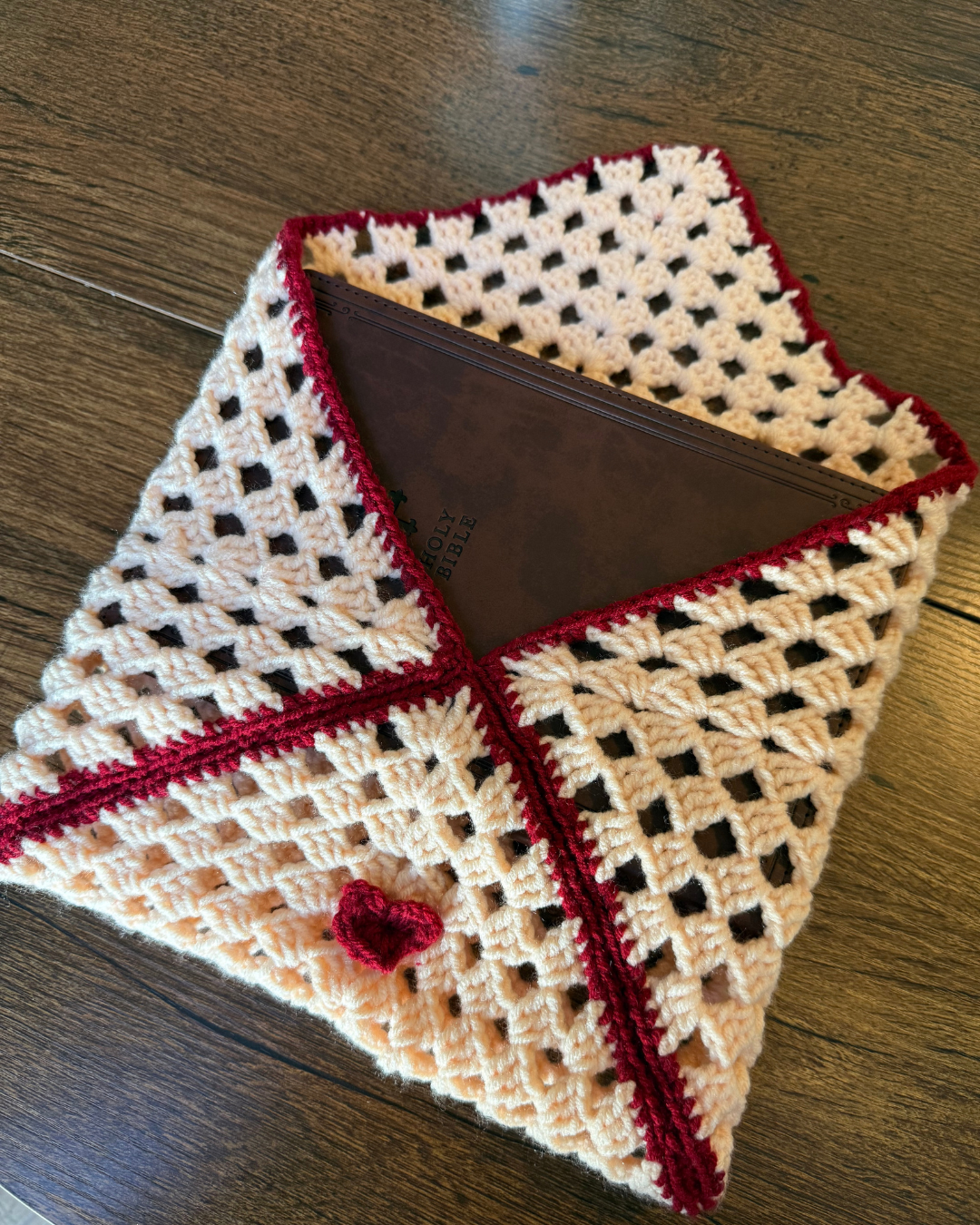 crochet-pink-and-red-heart-color-book-sleeve-on-brown-table.png