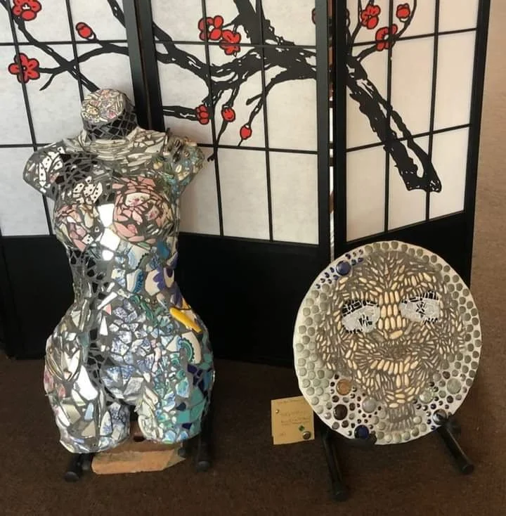 Mirror mosaic torso sculpture and mosaic face art displayed in front of a Japanese-style folding screen with cherry blossom branch design.