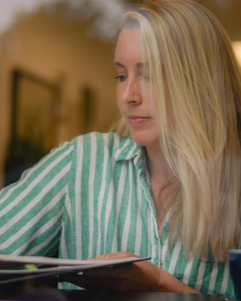 Ashley Doring wearing a green and white striped shirt, sitting indoors and looking to her left.