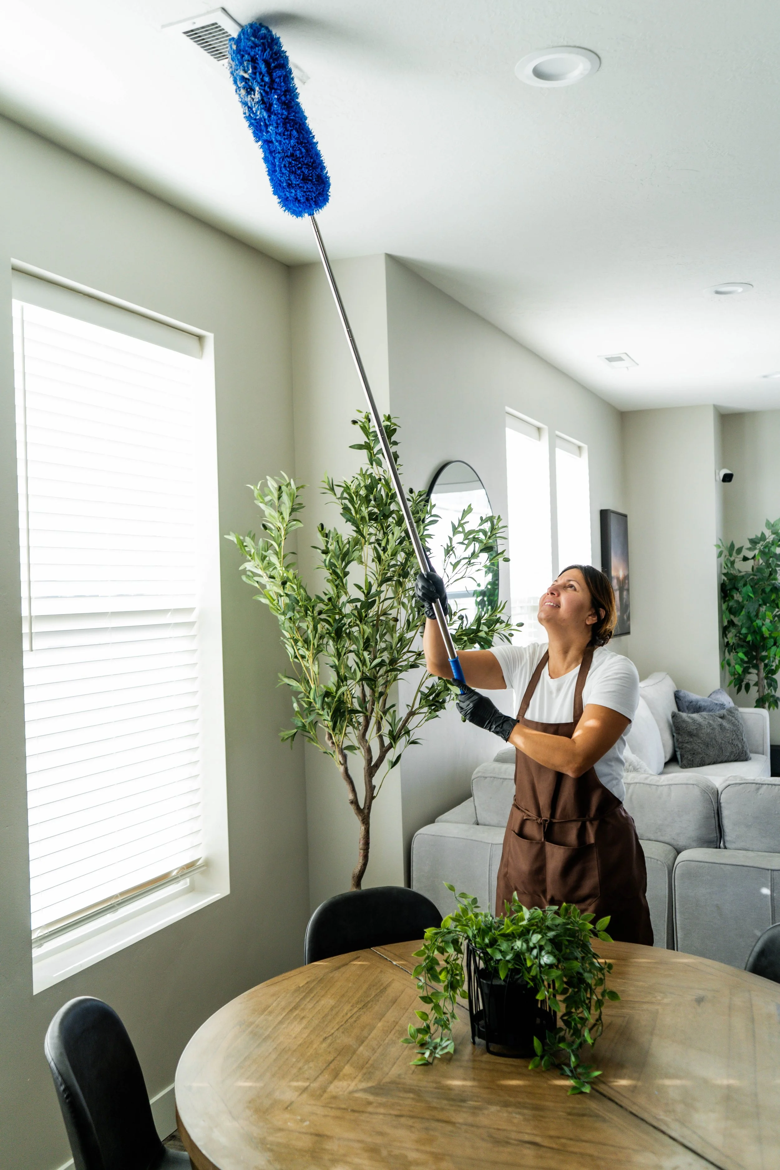 Deep cleaning technician dusting high air vent in Draper Utah luxury home