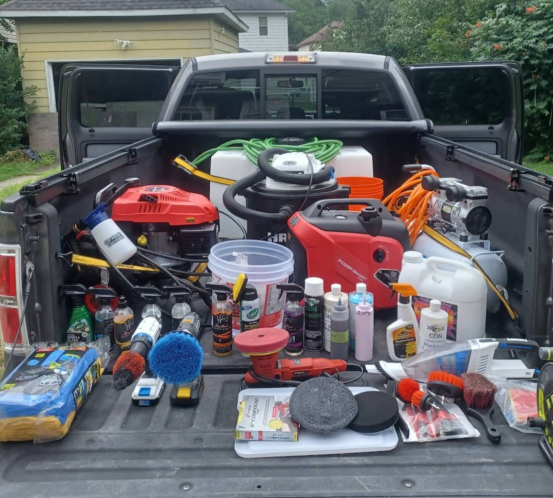 Arranged collection of cleaning and power tools, chemicals, and supplies in truck bed