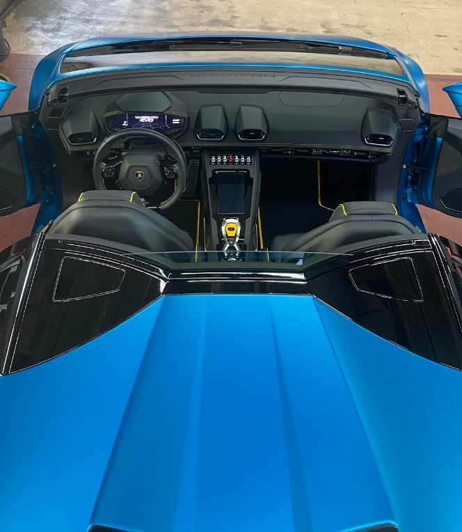 Interior view of a blue Lamborghini convertible sports car showing the dashboard, steering wheel, and front seats.
