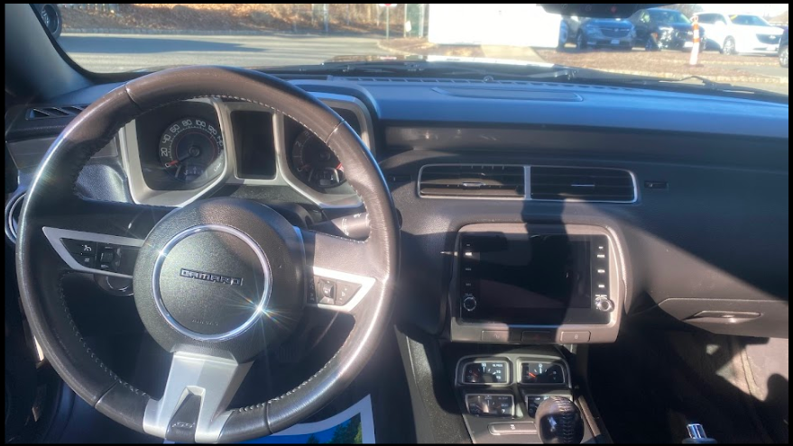 The interior of a Chevrolet Camaro car, showing the steering wheel, dashboard, and infotainment system.