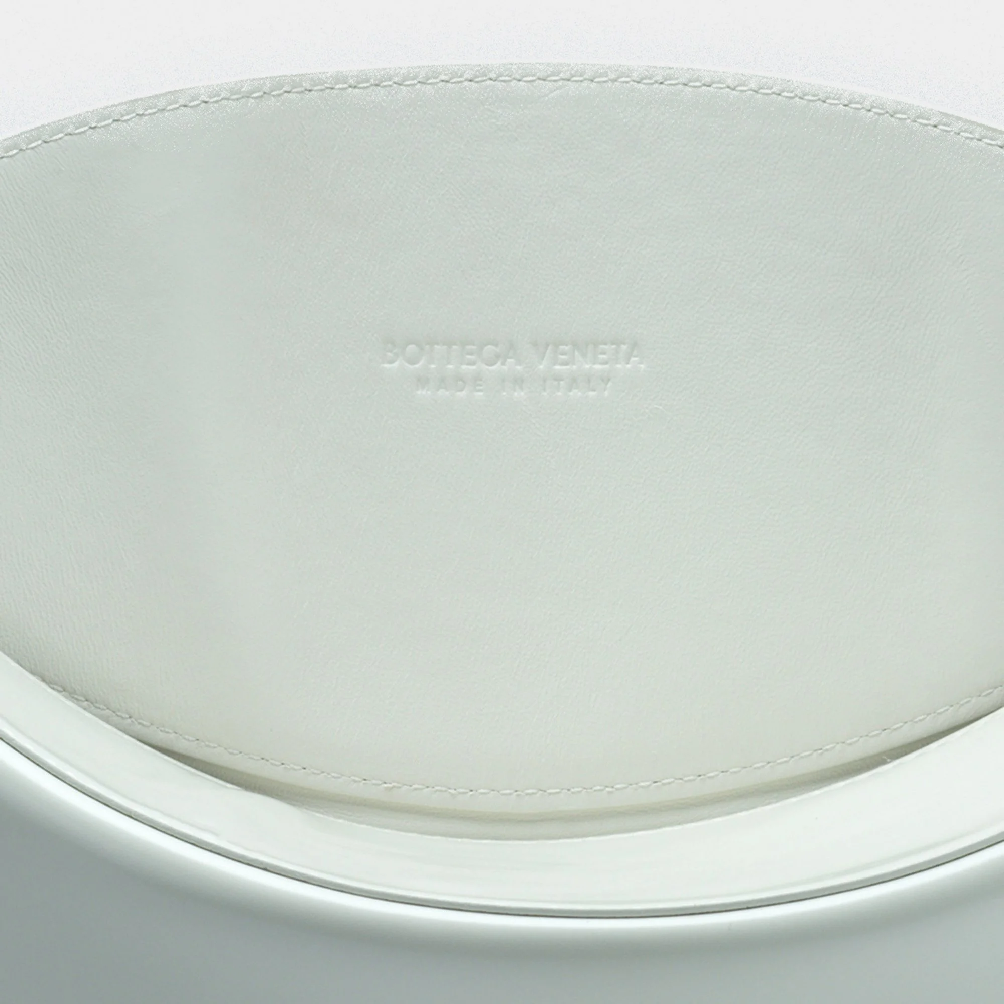Close-up of a white leather surface embossed with 'Bottega Veneta Made in Italy'.