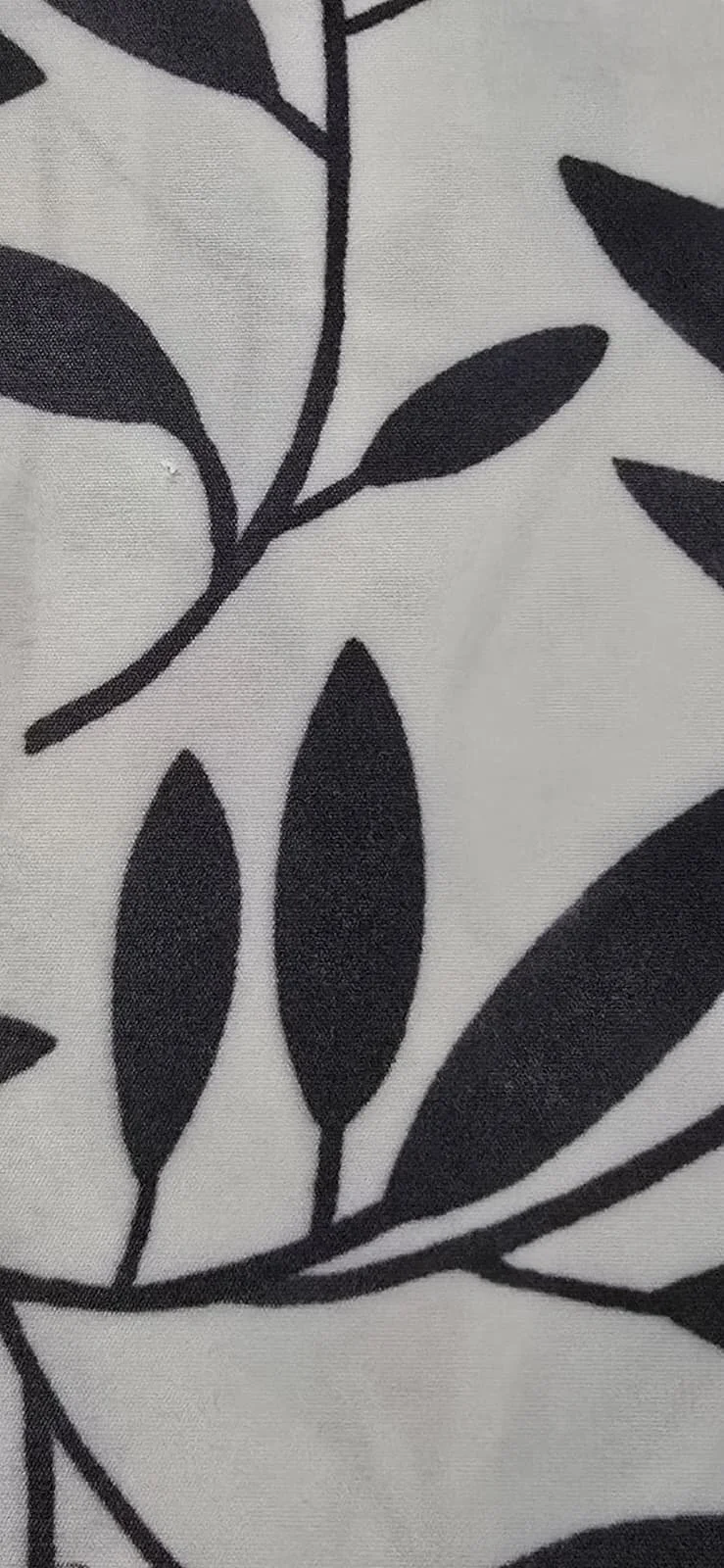 Close-up of fabric with black leaf and branch pattern on white background.