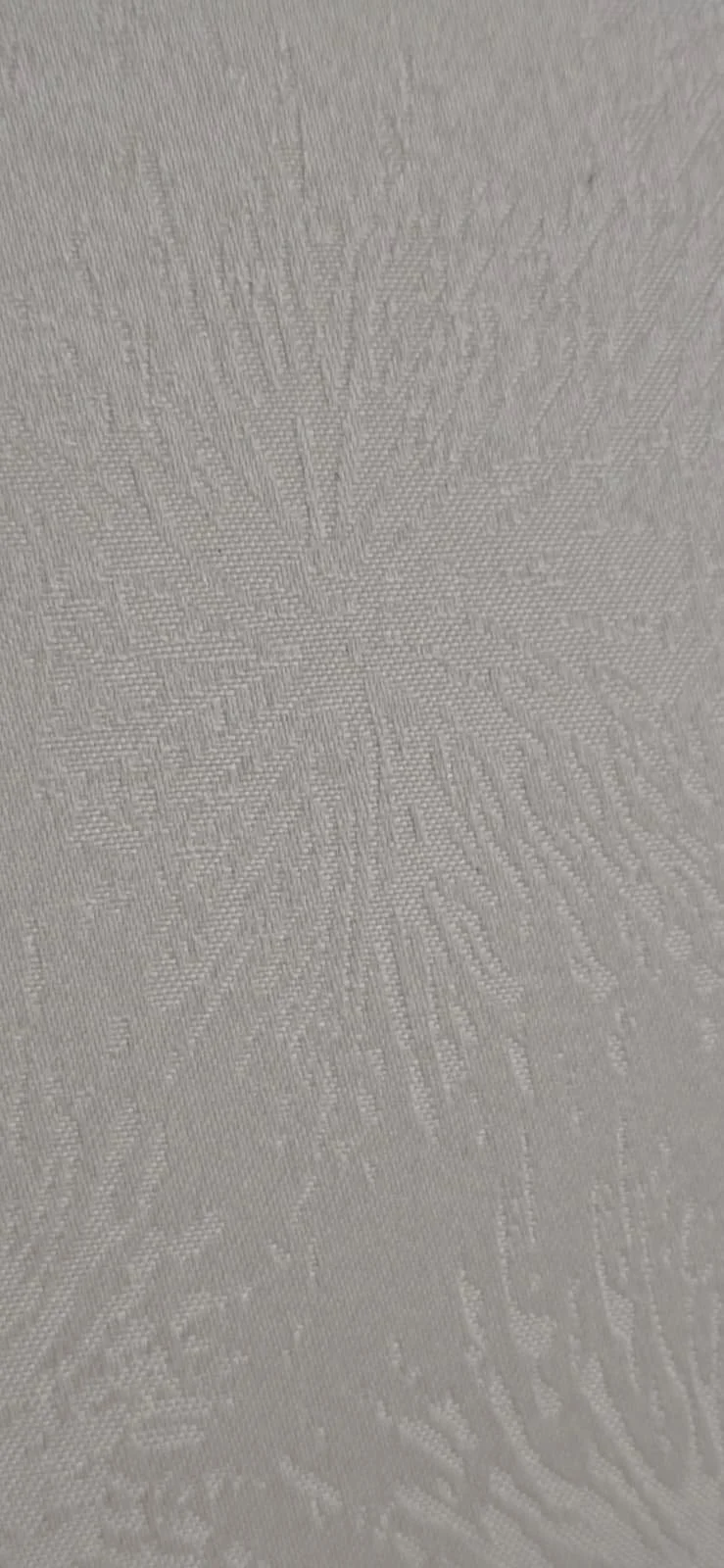 Close-up of a textured white fabric with a subtle, intricate pattern.