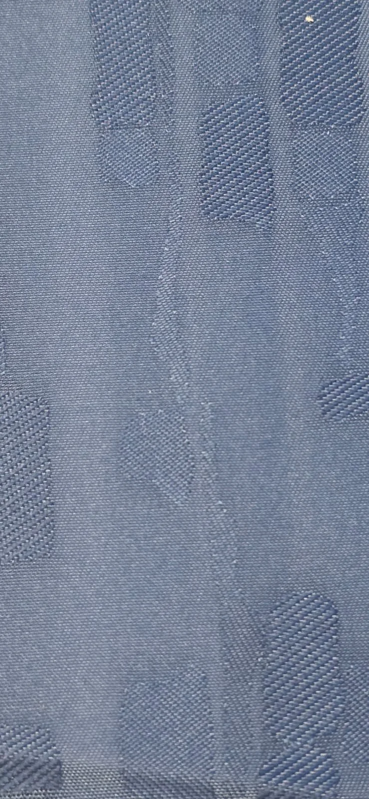 Close-up of a blue, textured fabric with a floral pattern woven into it.